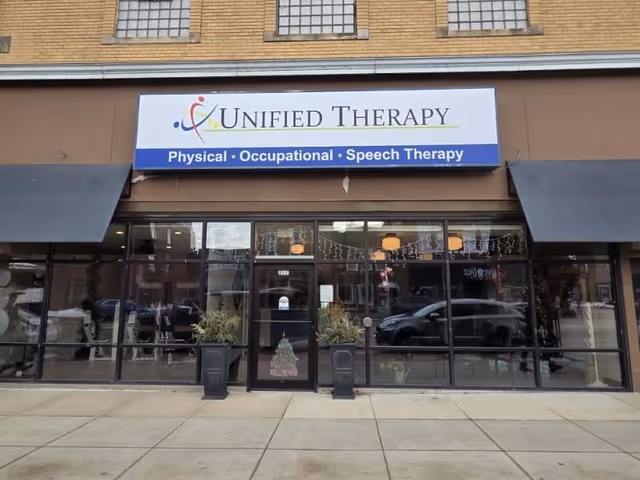 Frontal view of Unified Therapy storefront with sign, glass doors, and decorative windows.