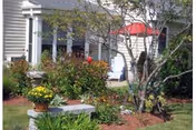 Front exterior of a senior living facility with landscaping and a red patio umbrella