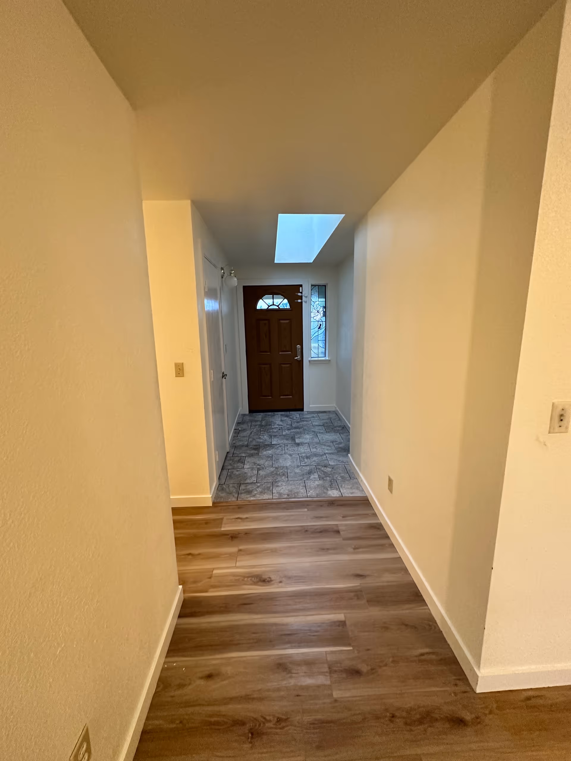 Narrow interior hallway of an adult family home, leading to a front door and tiled entry.