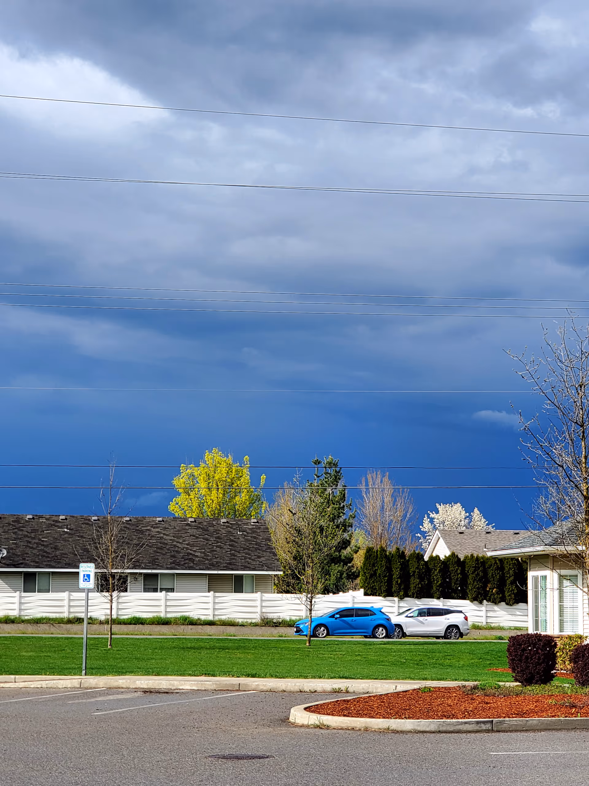 Exterior view of The Lodge at Bristol Heights with a grassy lot, trees, and parked cars.