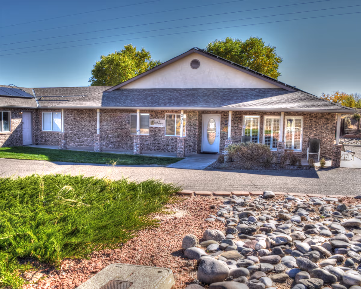 Single-story brick senior living facility with front entrance and stone landscaping.