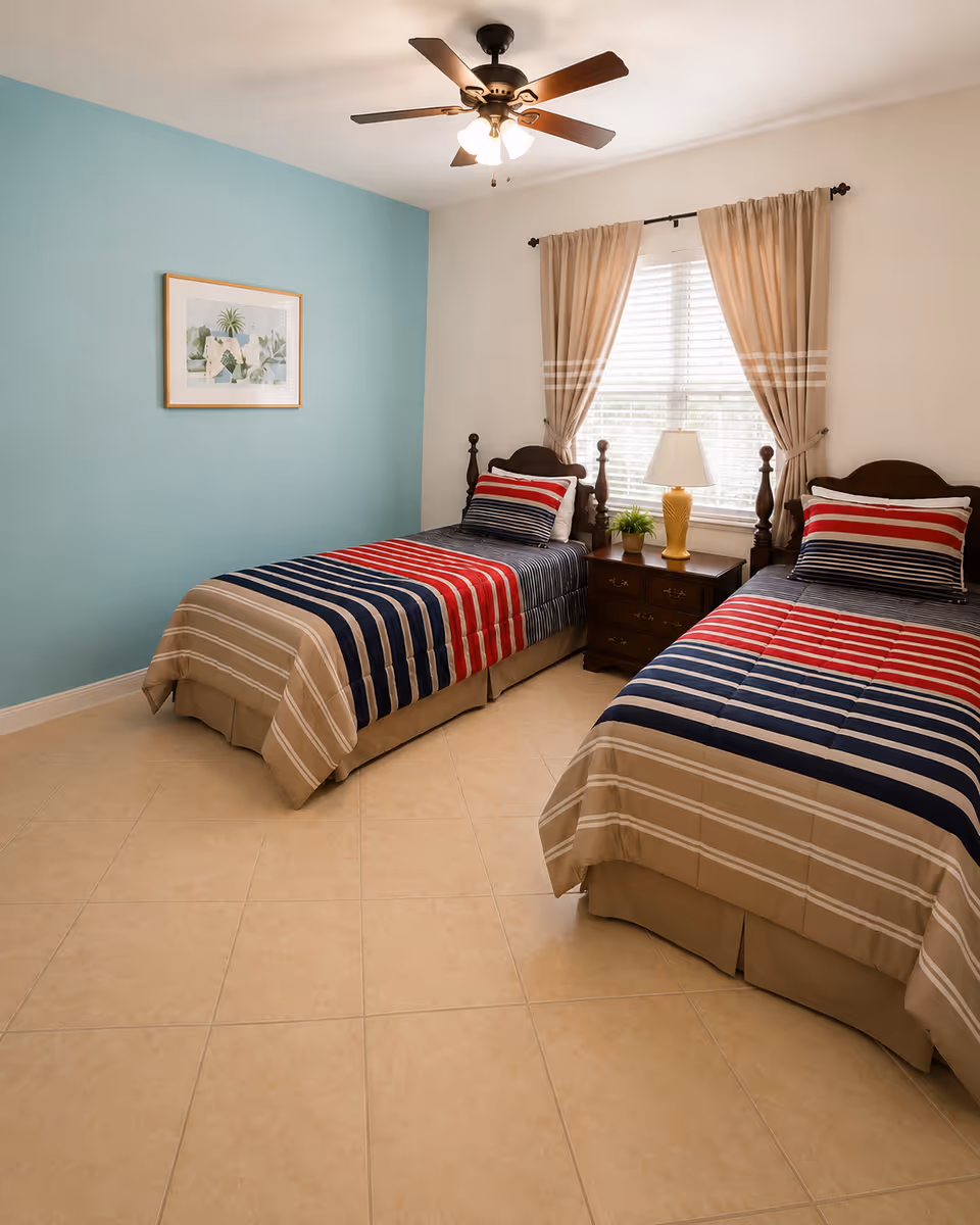 Two twin beds with striped bedding in a bright blue-accented bedroom.