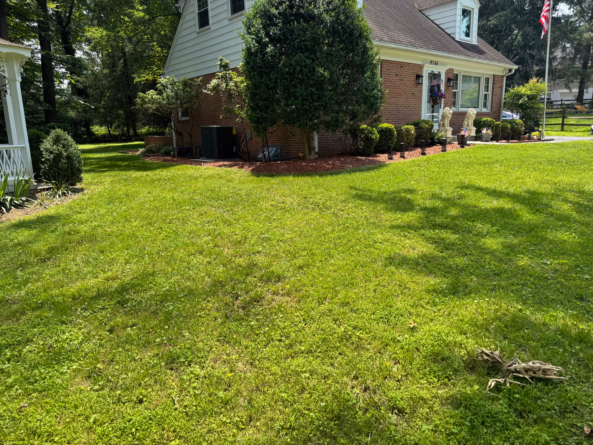Exterior view of a brick senior living home with a manicured lawn and statues.