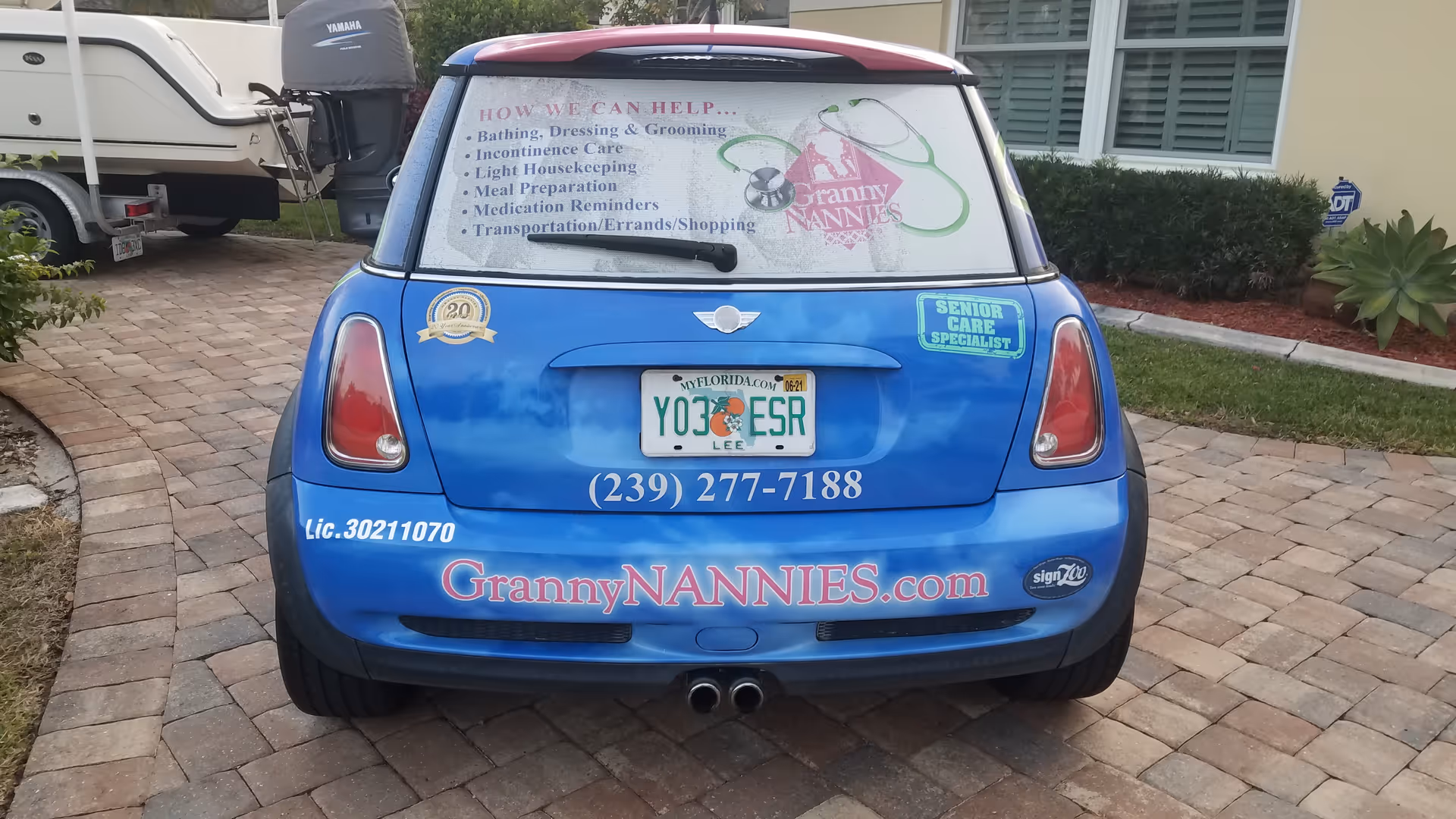 Blue GrannyNANNIES promotional car with decals parked on a brick driveway.