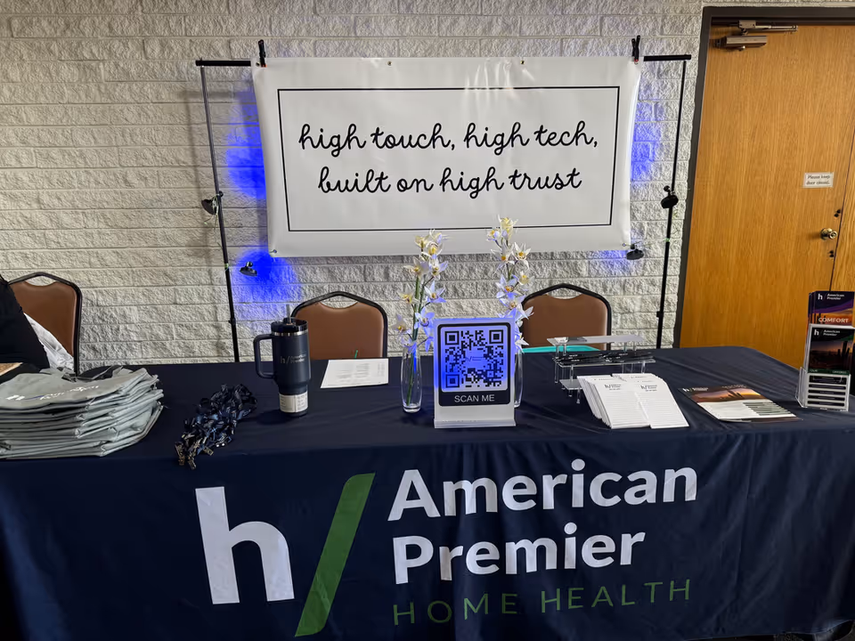 Indoor registration desk with American Premier branding, brochures, and a QR sign for attendees