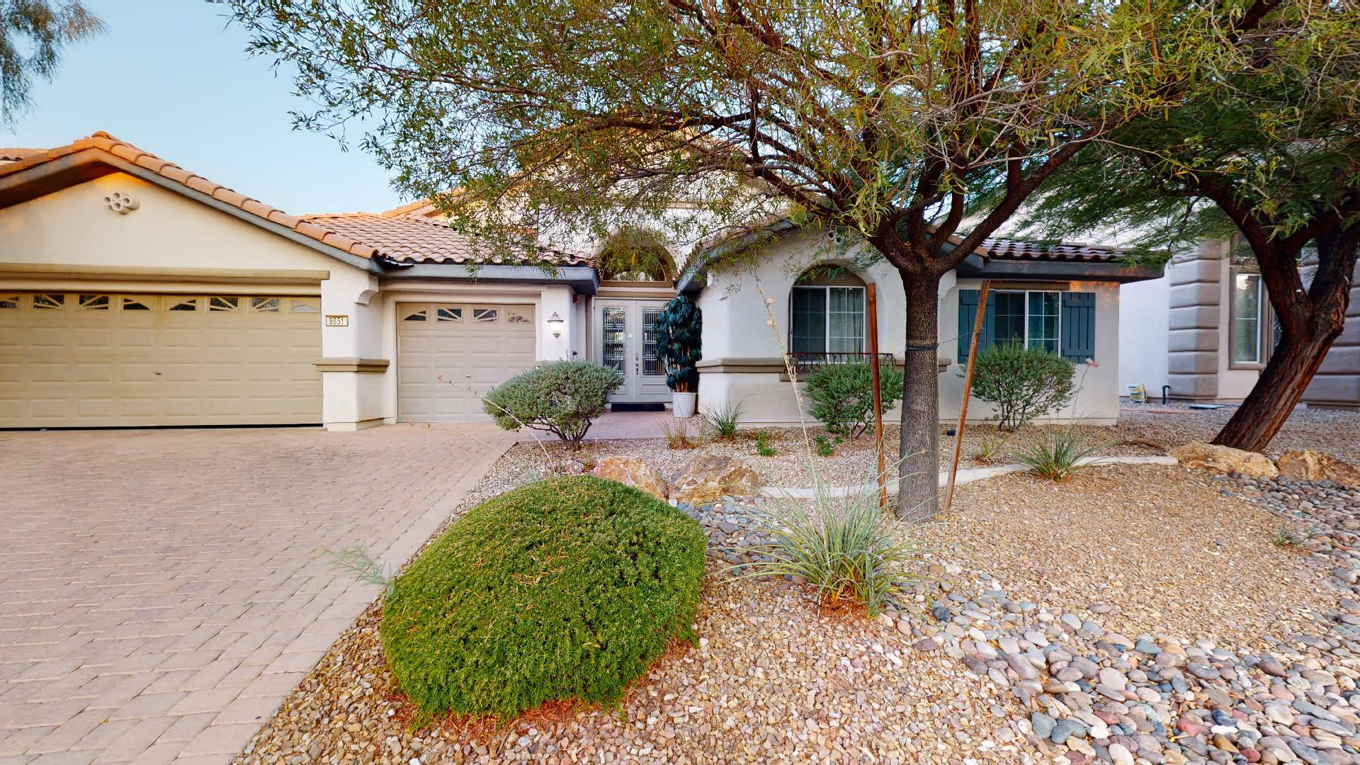 Front exterior of a single-story senior living home with desert landscaping and two garage doors
