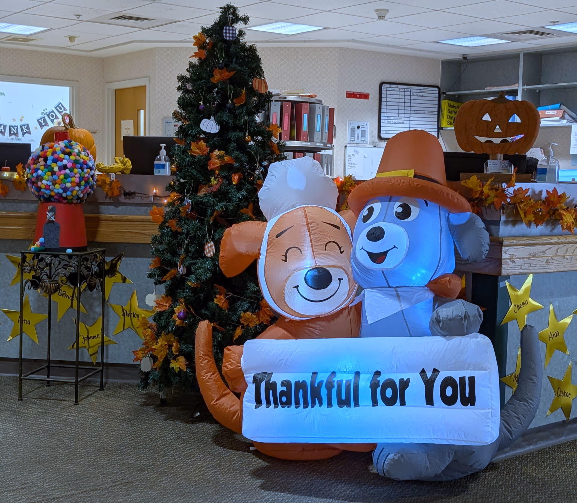 Indoor lobby featuring inflatable dogs, a Christmas tree, pumpkins, and autumn garland.
