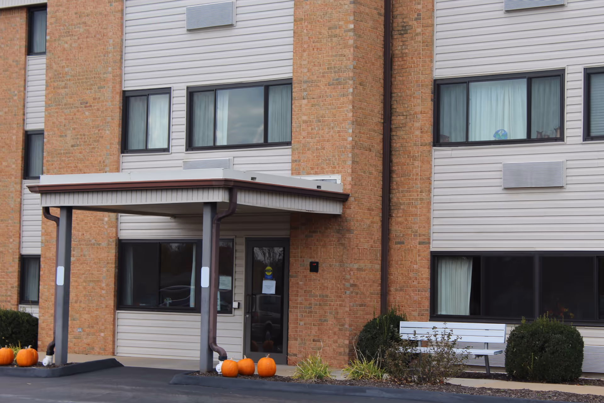 Exterior view of St Patricks II Apartments entrance with pumpkins and a bench.