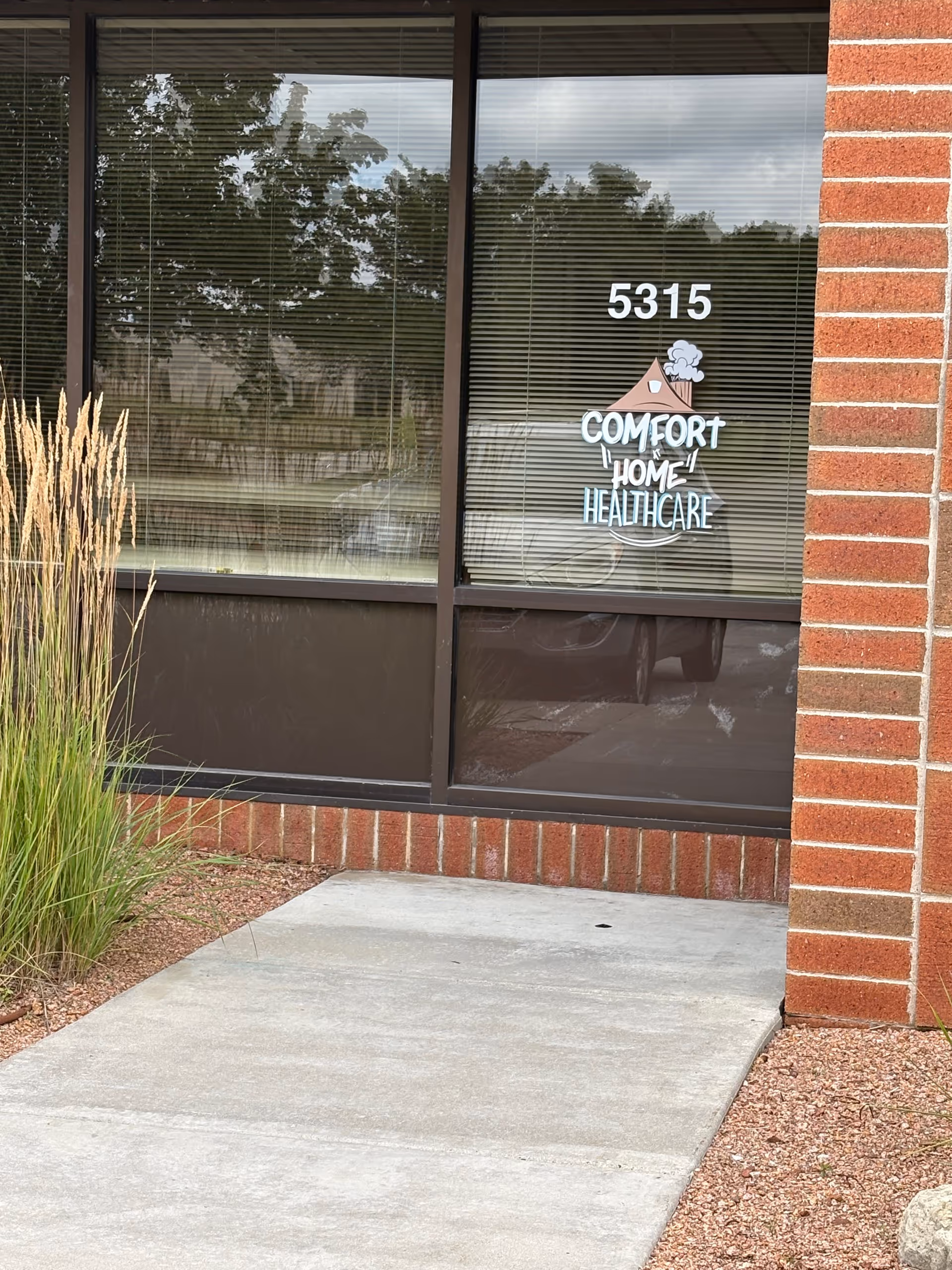 Front exterior of a brick building with window logo for Comfort At Home Healthcare