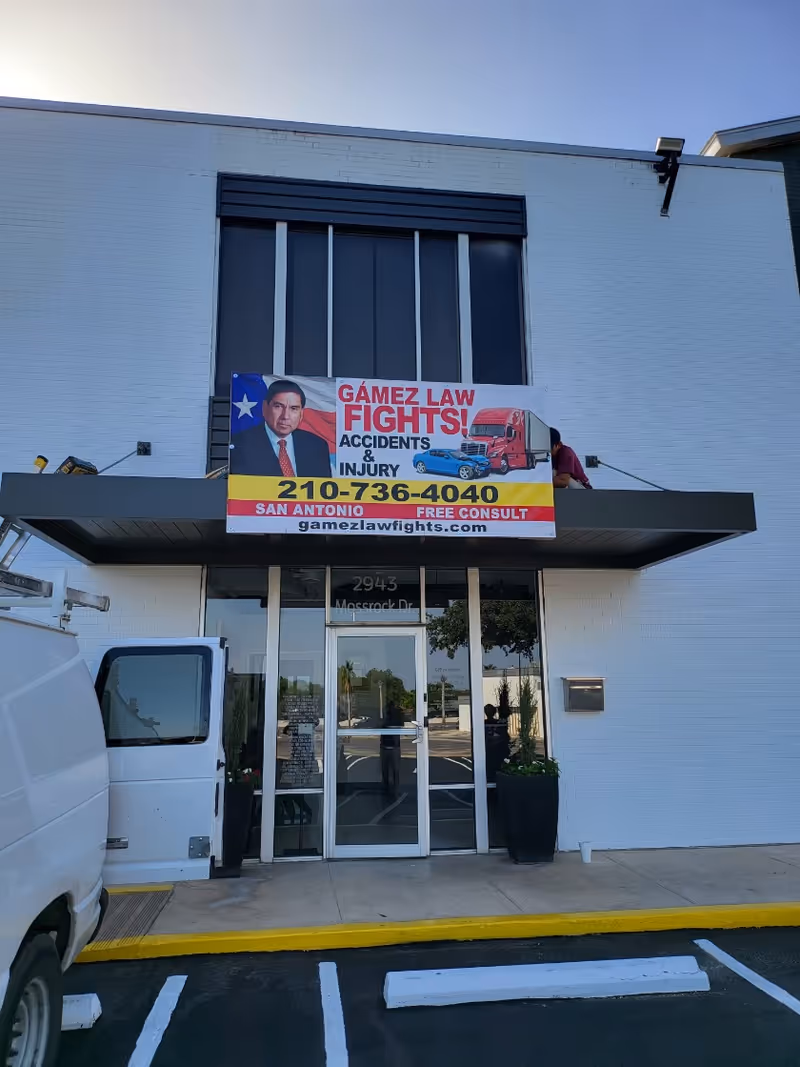 White commercial building exterior with a large banner advertising a law firm above the entrance.