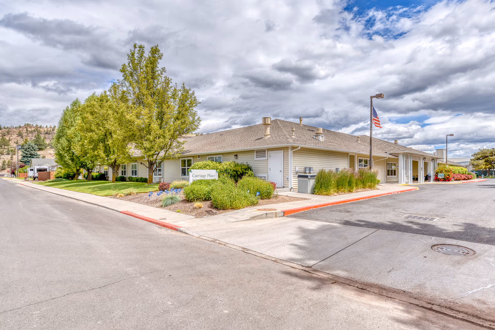 Carriage Place Memory Care exterior: a single-story building with landscaped front yard and flagpole.