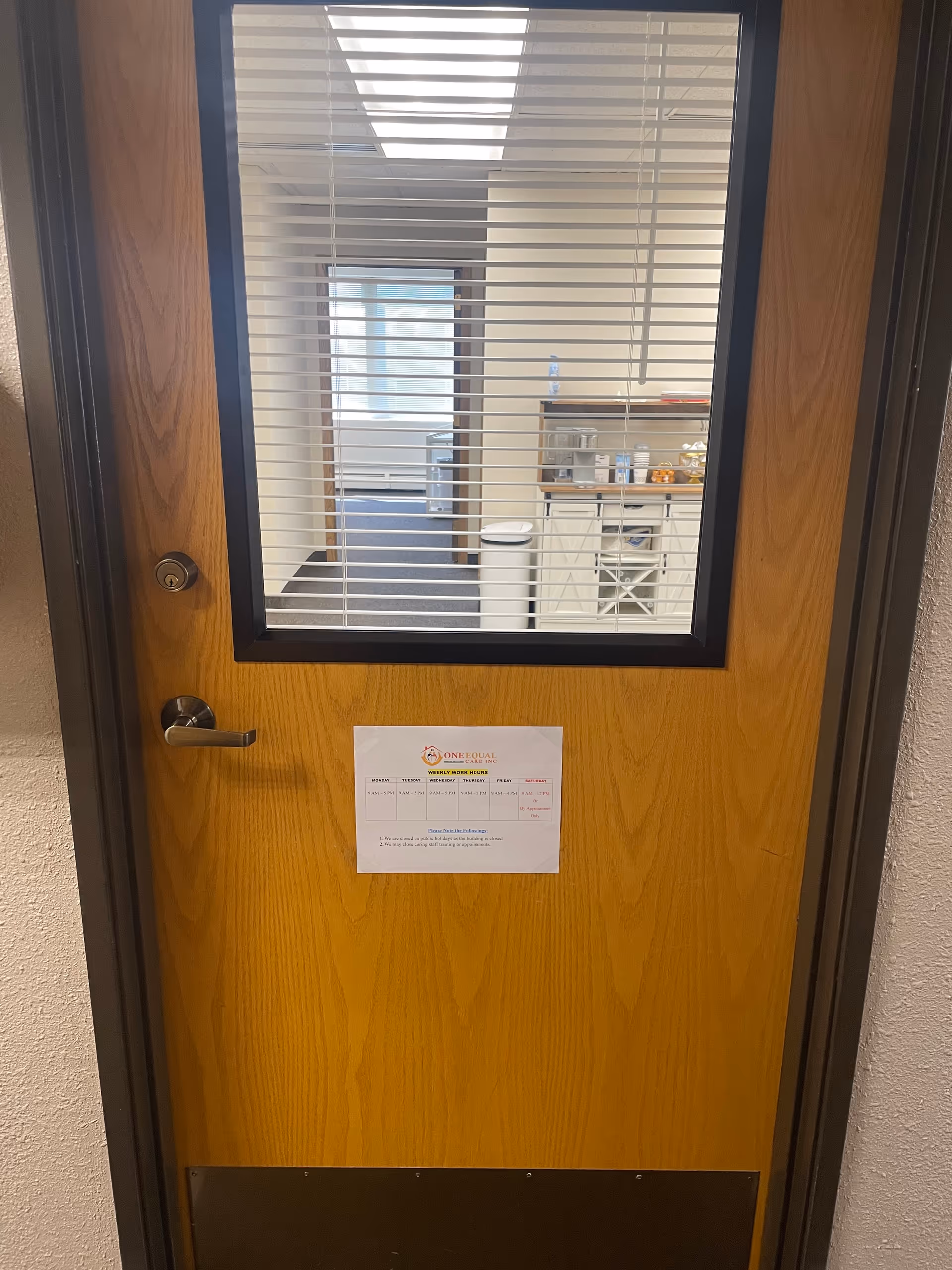 Wooden door with blinds reveals a small staff kitchenette beyond.