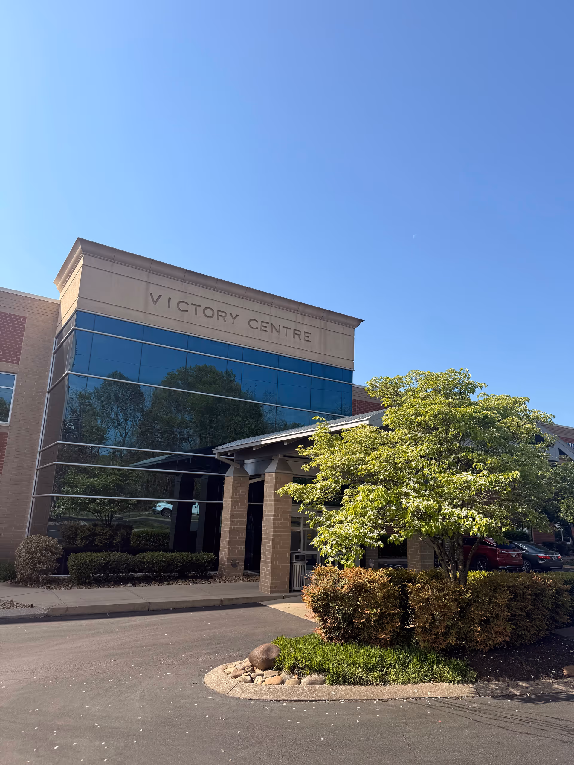Exterior view of a modern Victory Centre building with glass facade and landscaping.