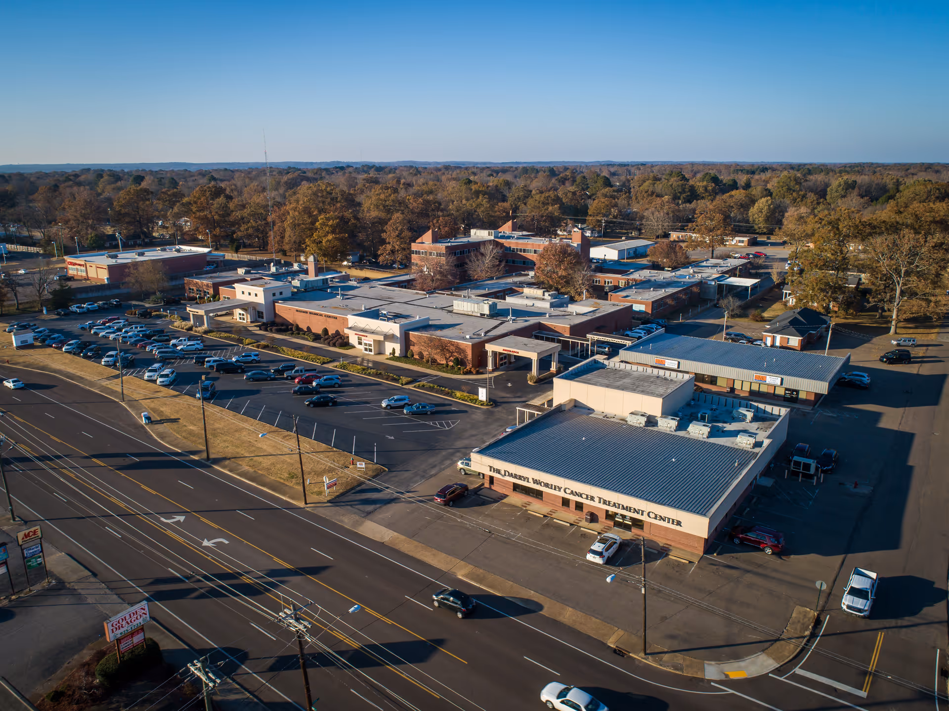 Aerial view of a medical center complex with multiple low-rise buildings, parking lots, and surrounding roads.