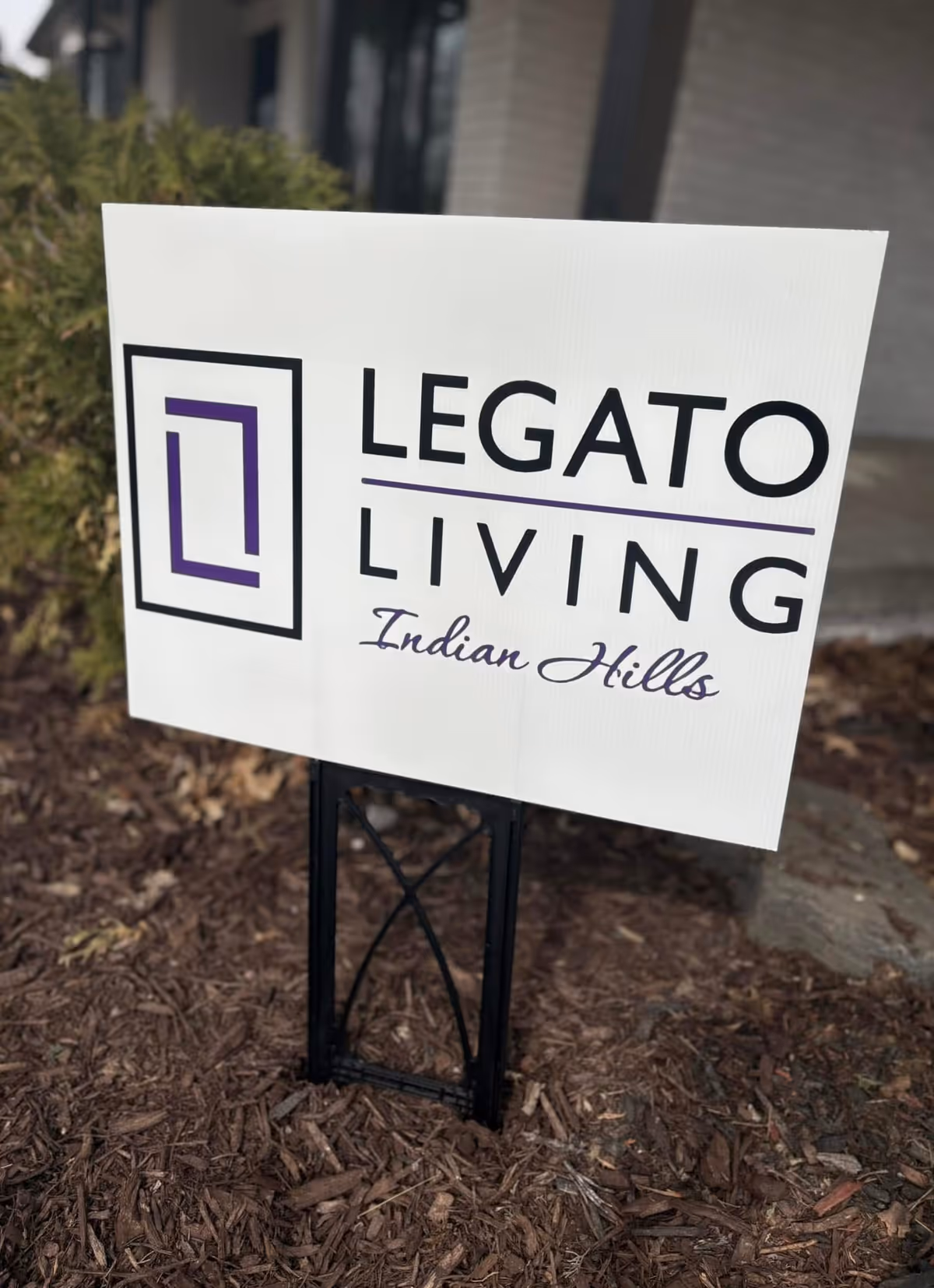 Legato Living Indian Hills sign outside on mulch with building behind