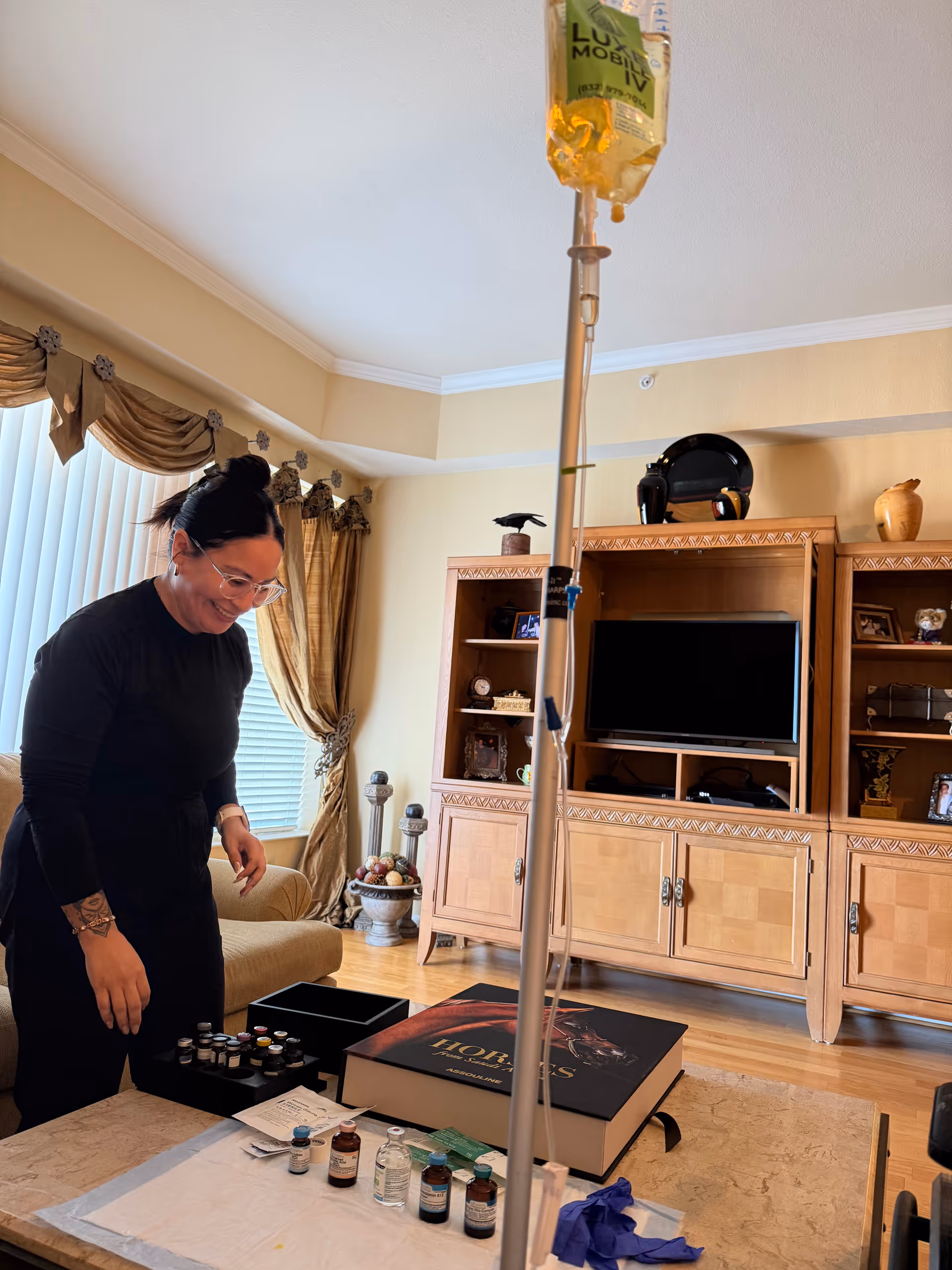 Caregiver prepares IV equipment in a living room with bottles on a coffee table.