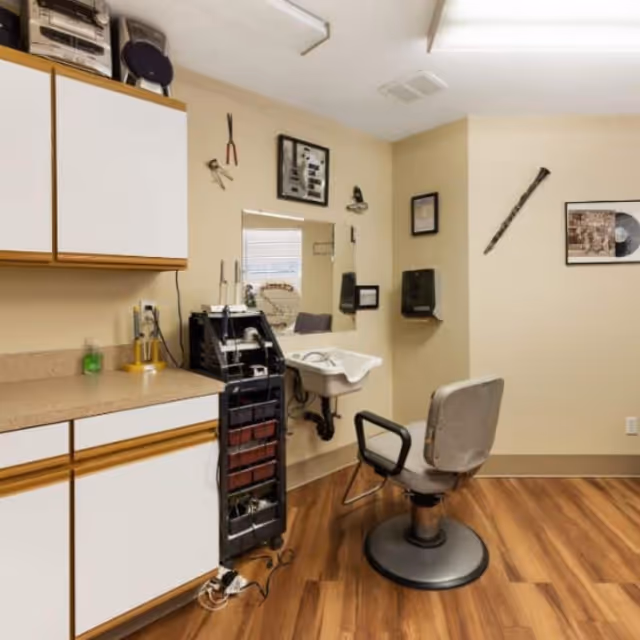 Interior of senior living facility salon with chair, sink, cabinets, and tools.
