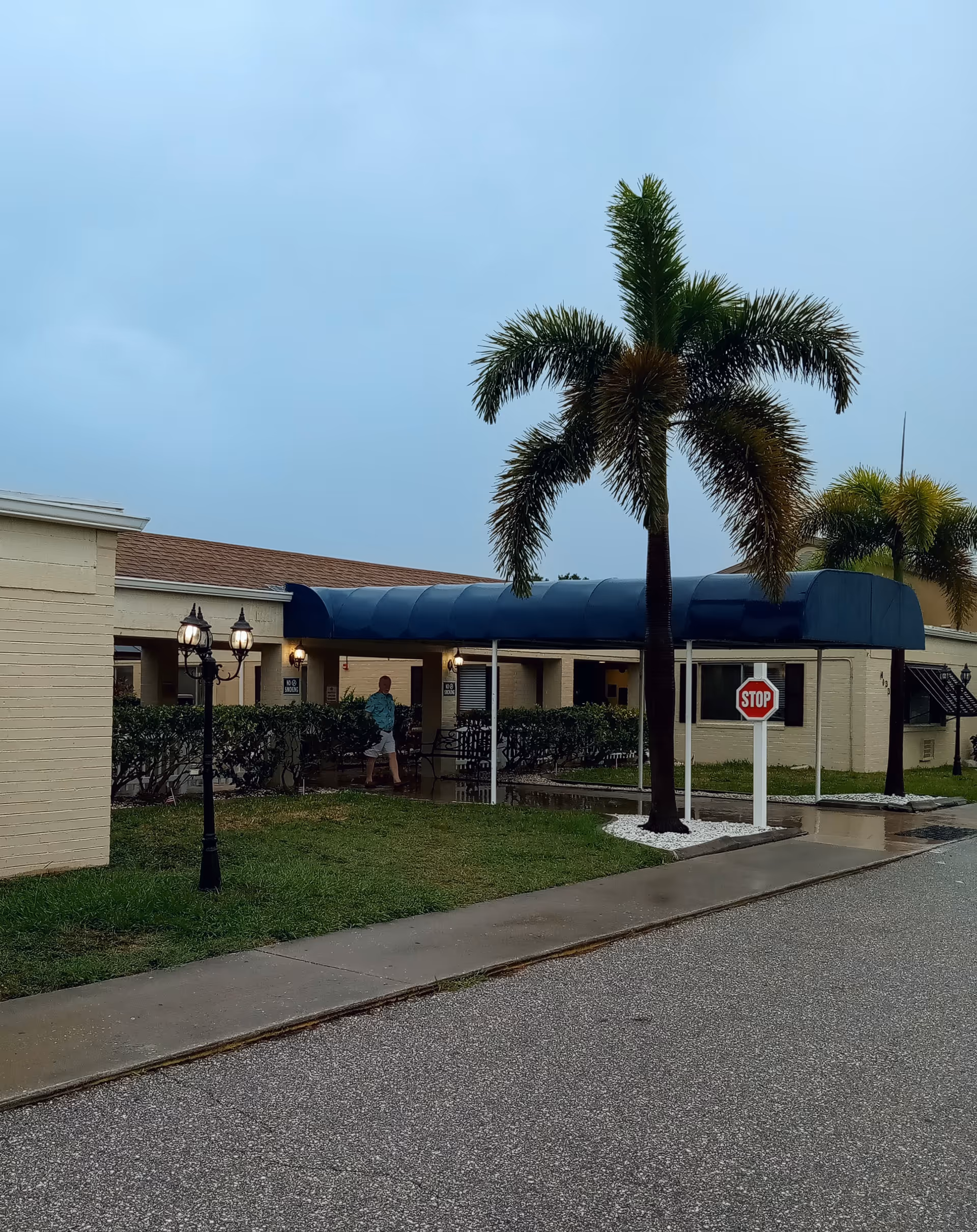 Exterior view of Charlotte Bay Rehabilitation & Care Center with palm trees and blue canopy.