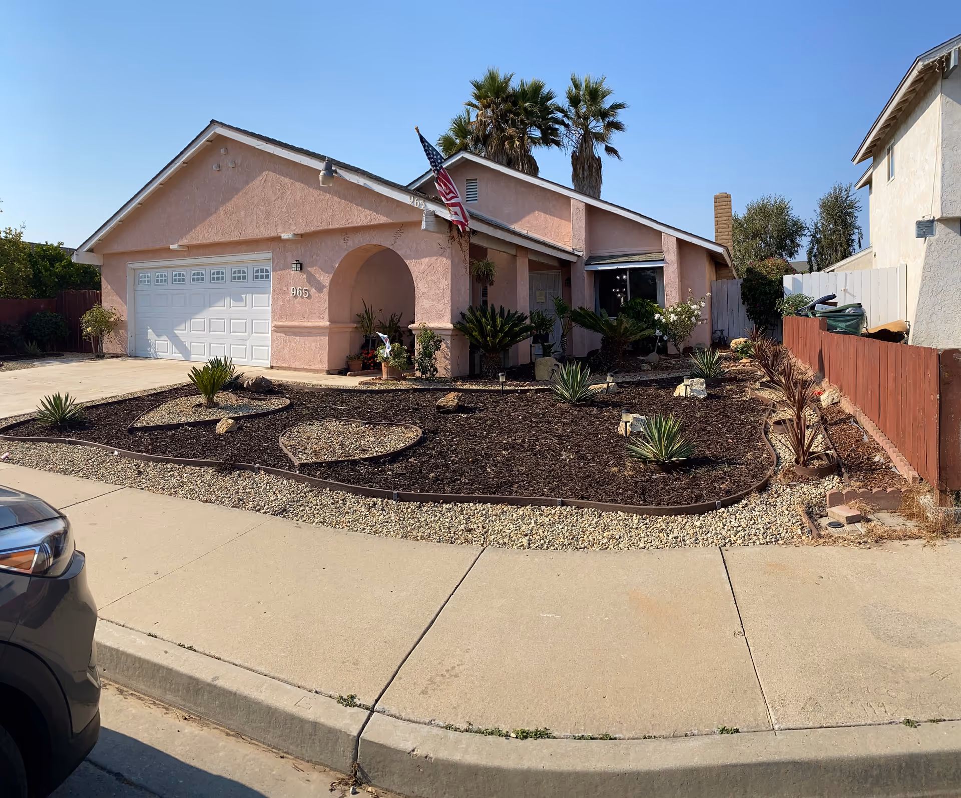 Pink single-story home with arched entry and desert landscaping in the front yard.