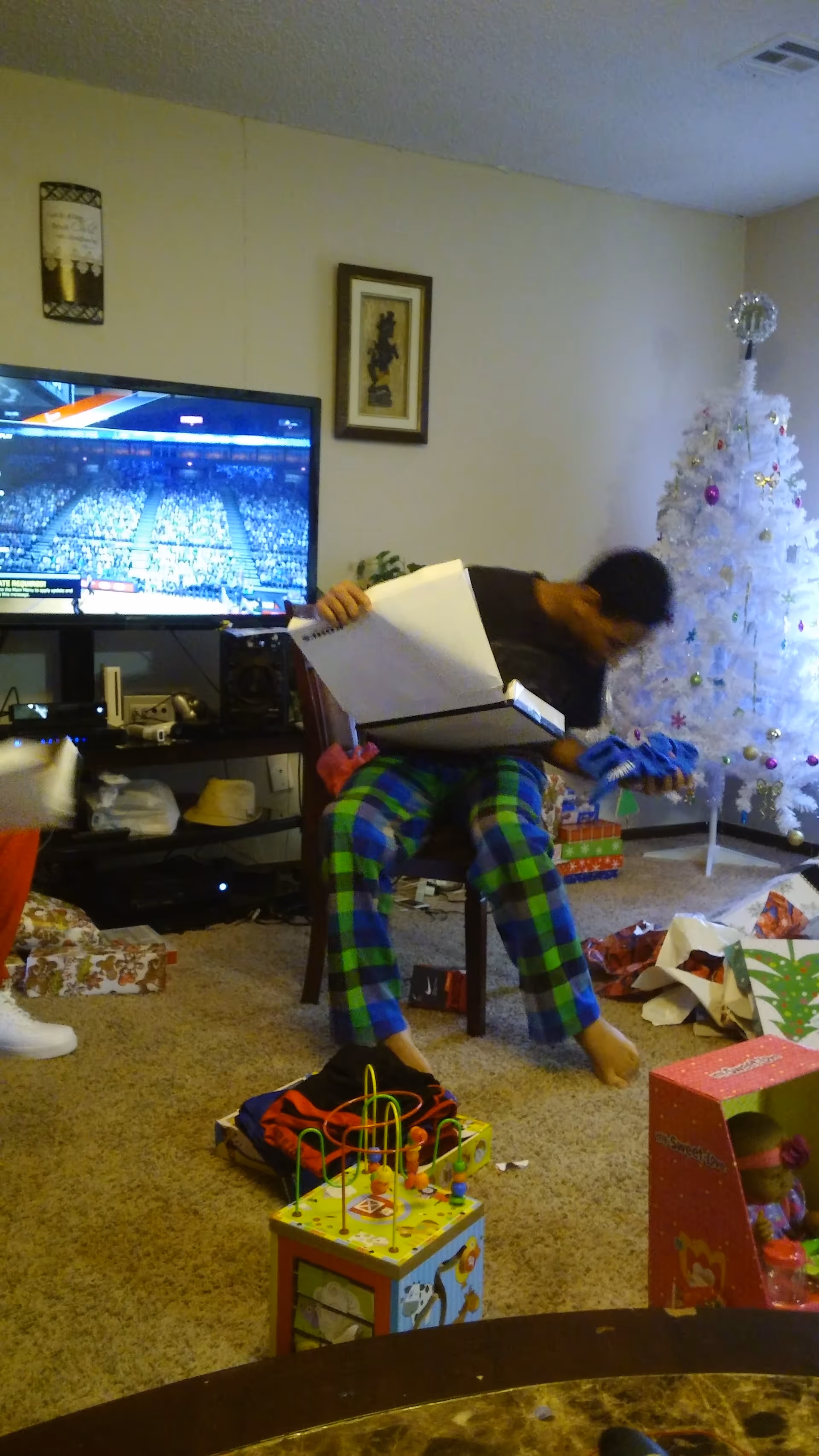 Resident opens a large box while seated in a cozy living room with a Christmas tree.