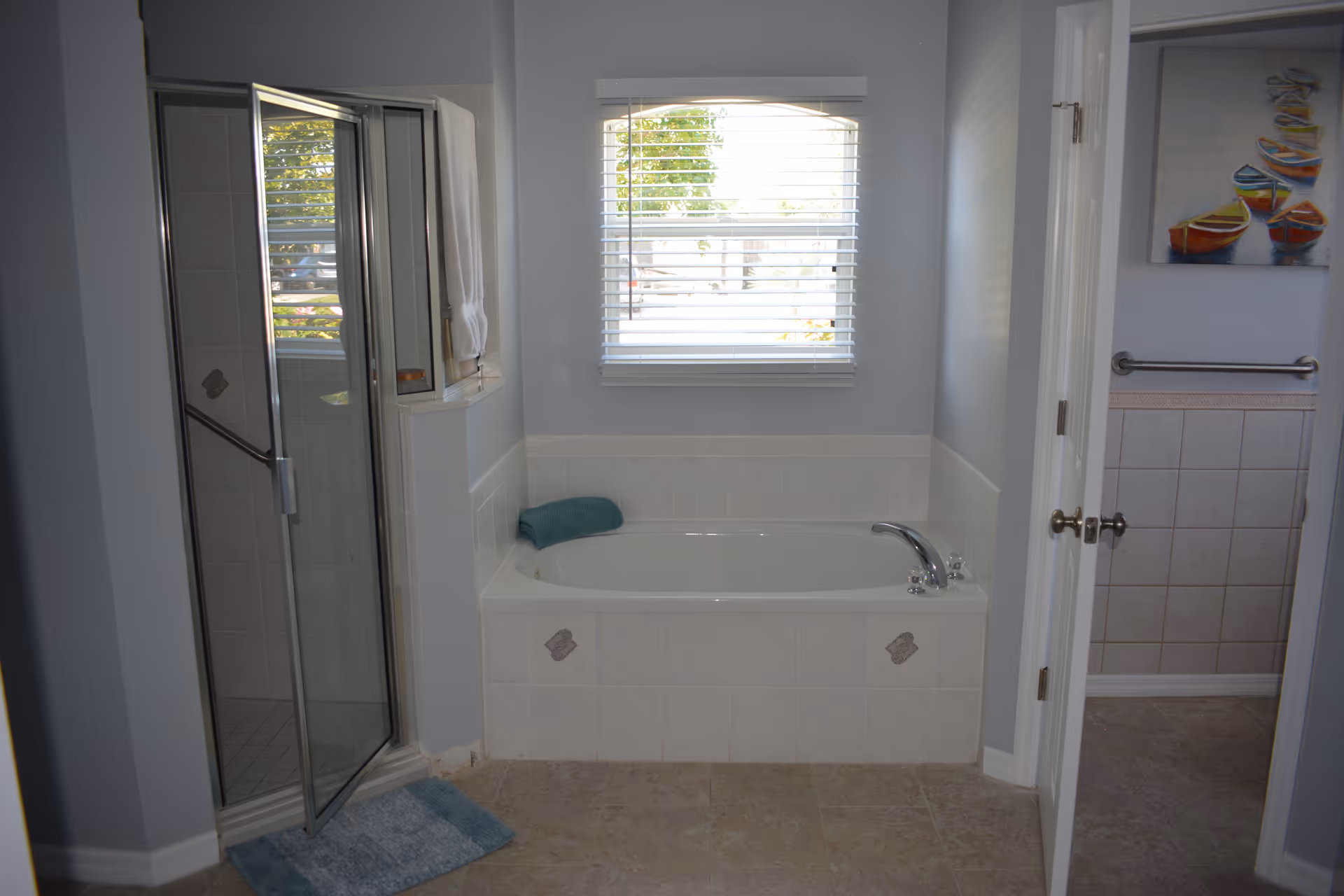 Bright bathroom with a built-in tub, glass shower, and window.