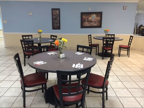 Pastel dining area with round tables, chairs, and flower centerpieces.
