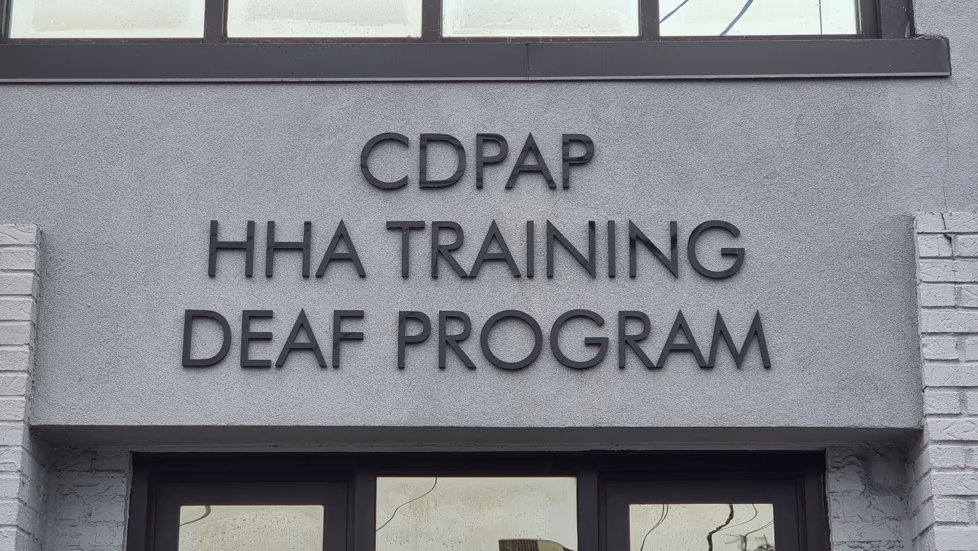 Exterior building entrance with a sign reading CDPAP HHA Training Deaf Program.