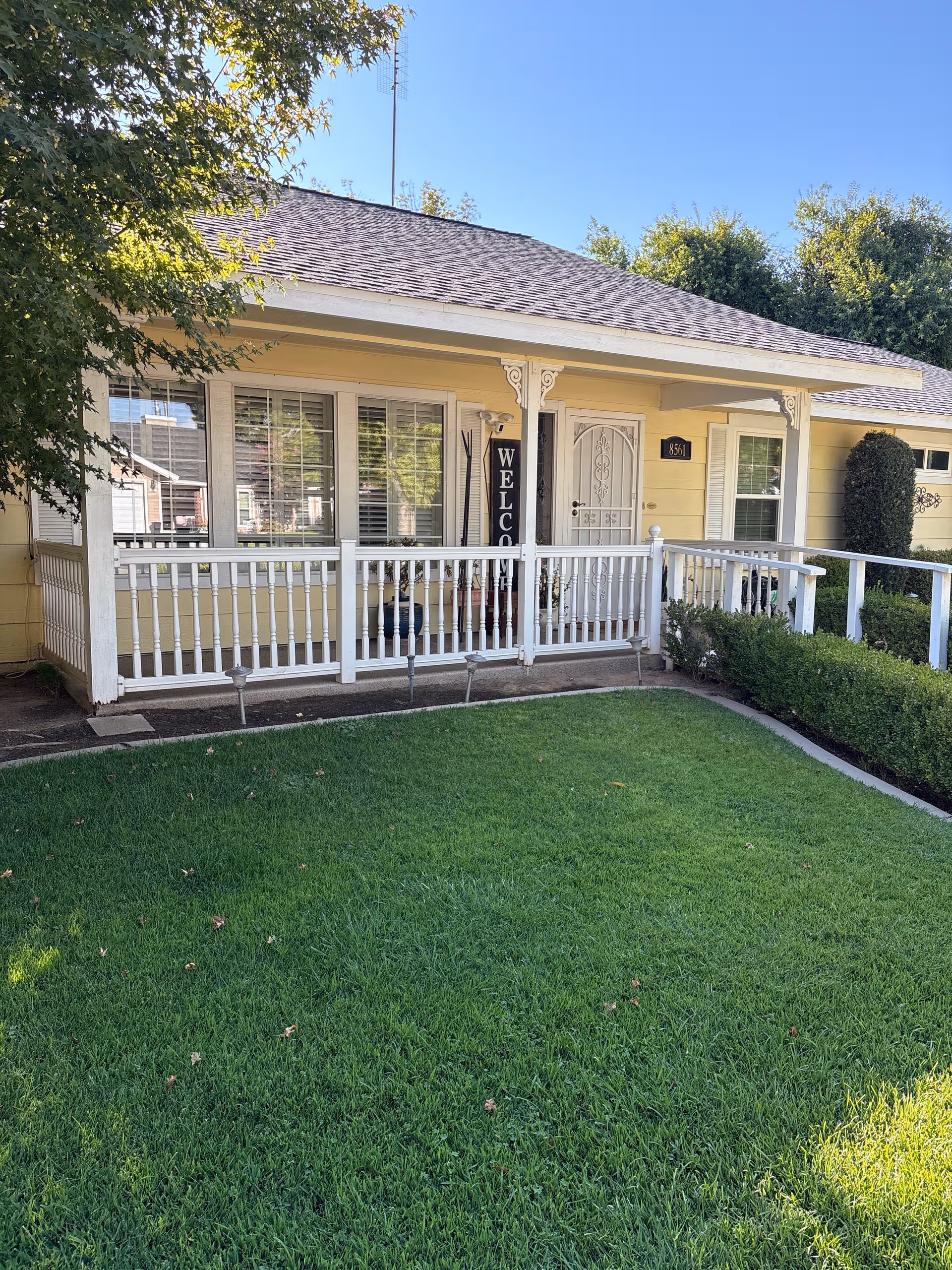 Single-story Jade Care Homes front porch with white railing and well-kept green lawn.