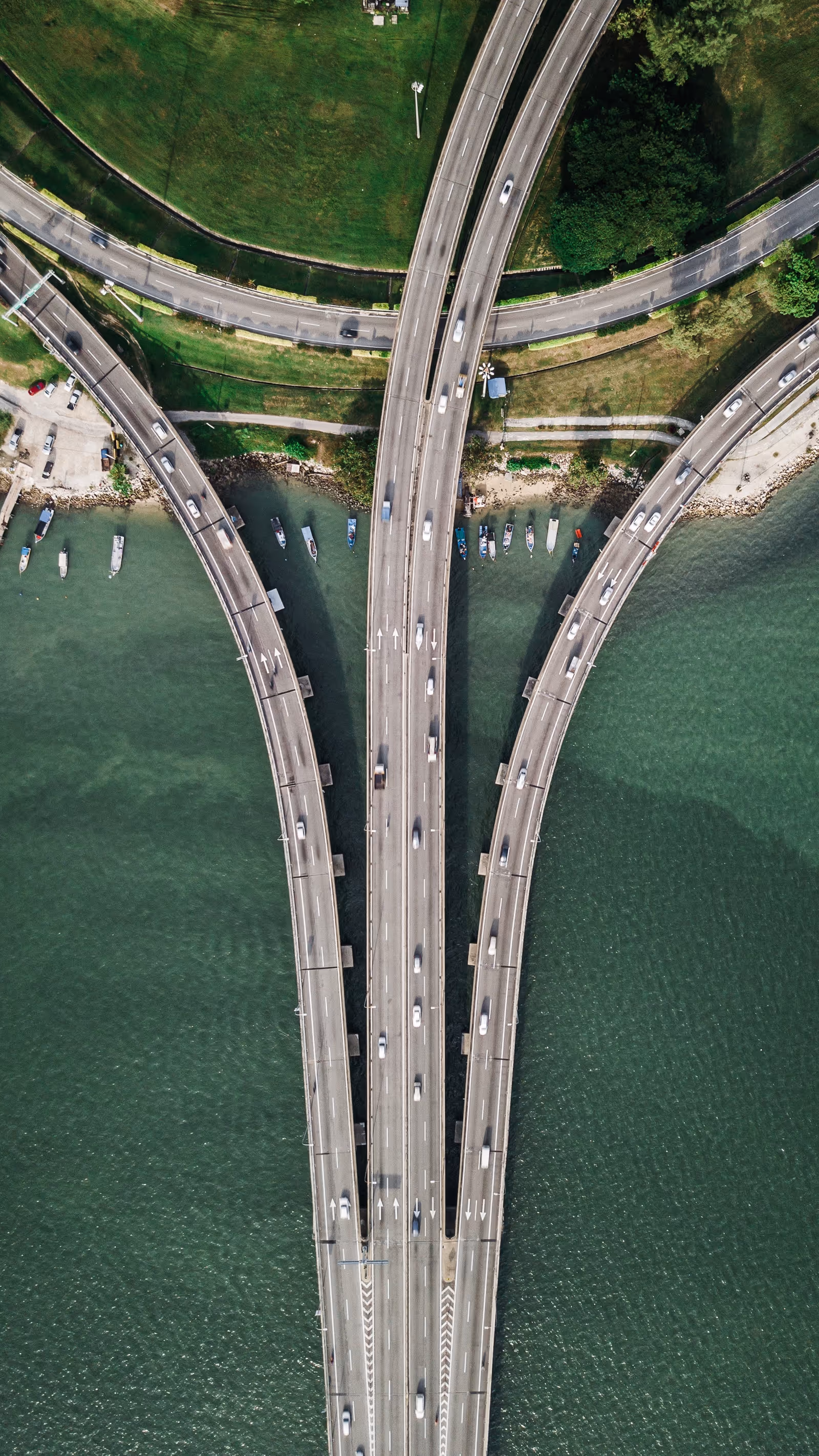 Aerial view of a multi-arch bridge crossing a river with green banks