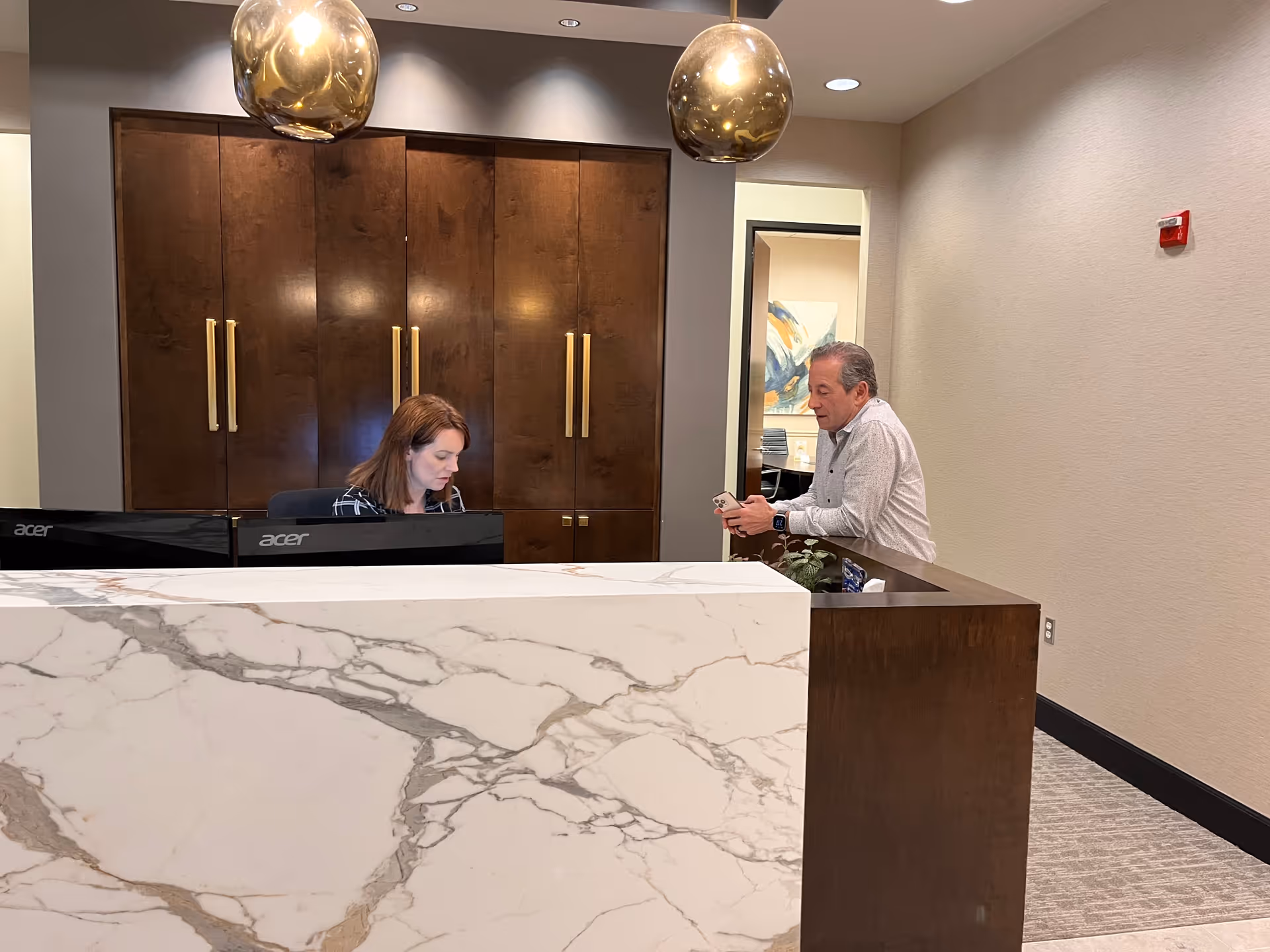 Reception area with marble counter and two staff members in a lobby