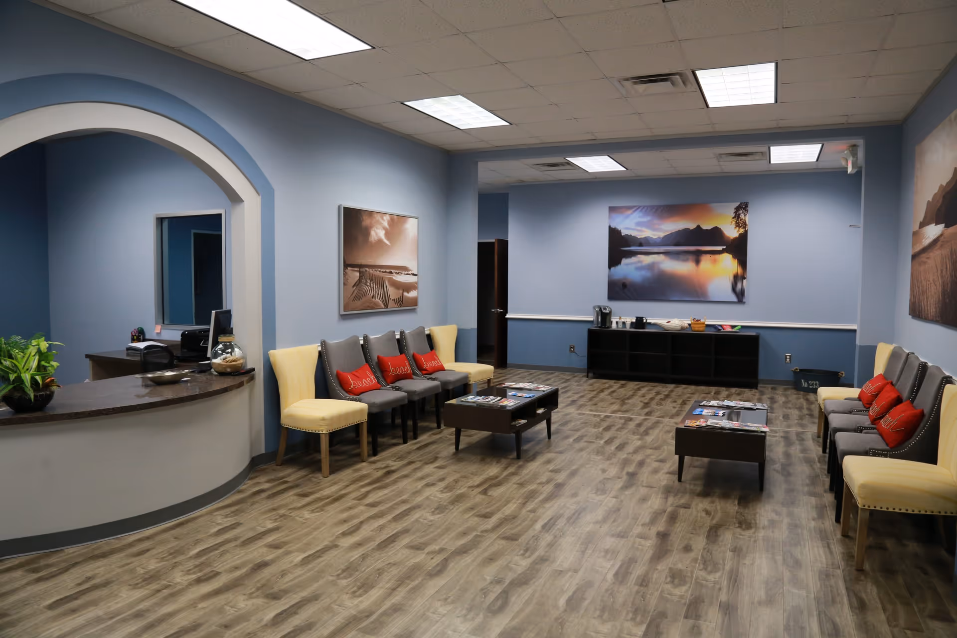 Spacious blue-walled lounge with seating, coffee tables, and landscape art.