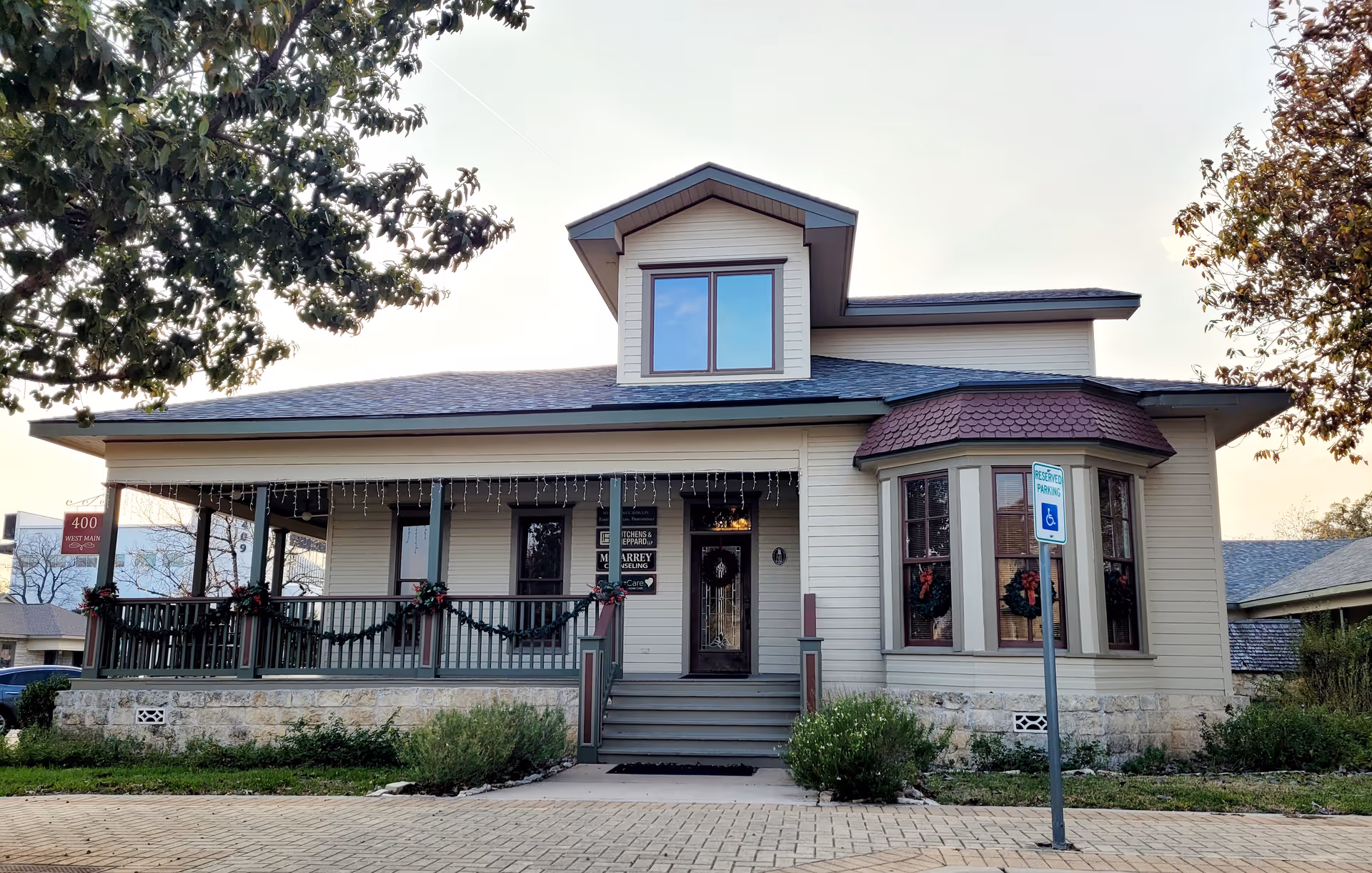 A welcoming house-style senior care building with a front porch and holiday garland.