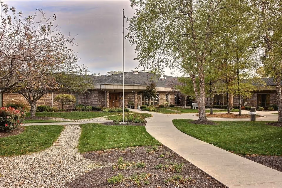 Brick exterior of a senior living center with curved walkway and green lawns.
