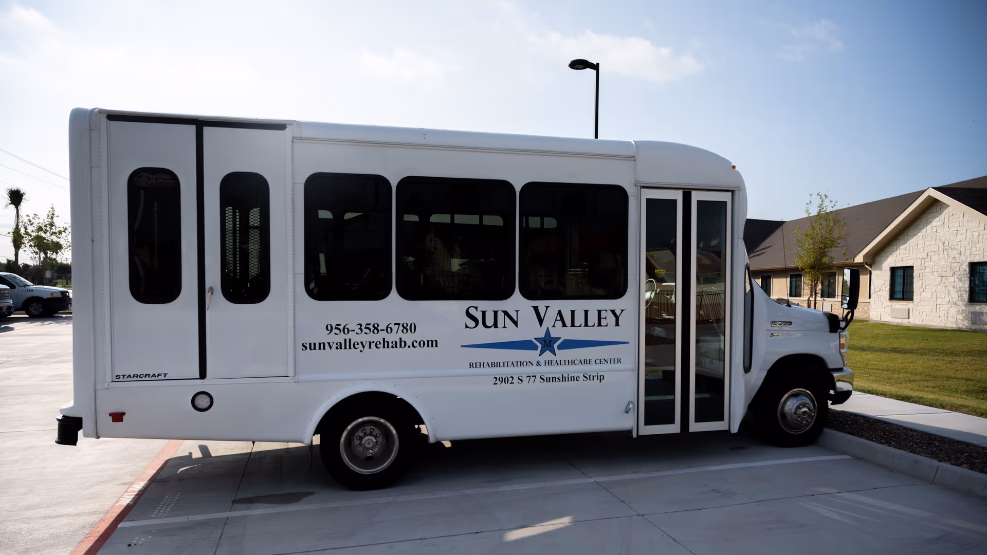 White Sun Valley Rehabilitation and Healthcare Center bus parked in a lot beside a beige facility.