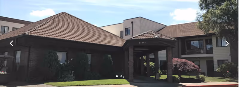 Exterior view of King City Senior Village with a covered entrance and manicured shrubs.