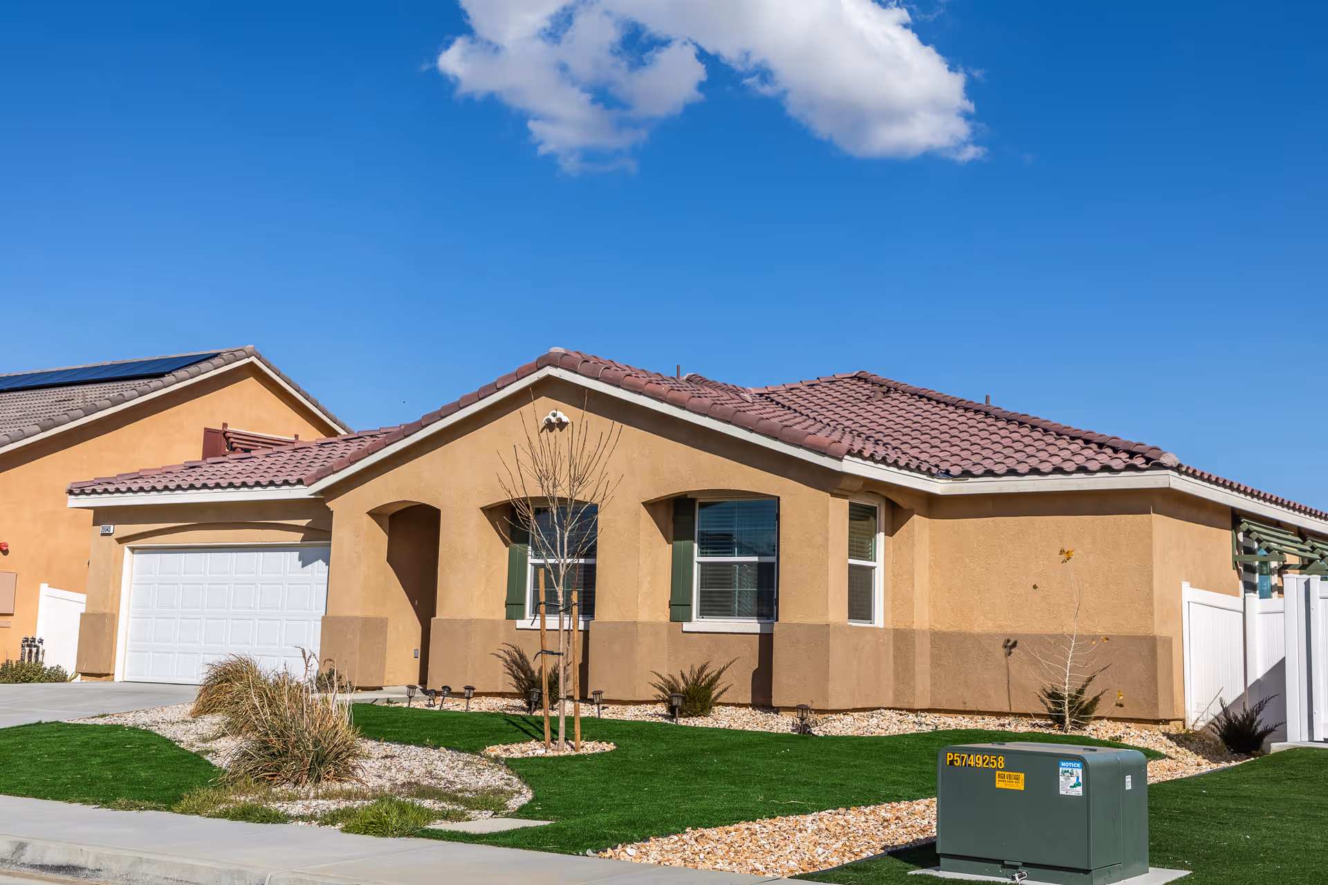 Single-story tan building with a red-tiled roof and manicured front yard.