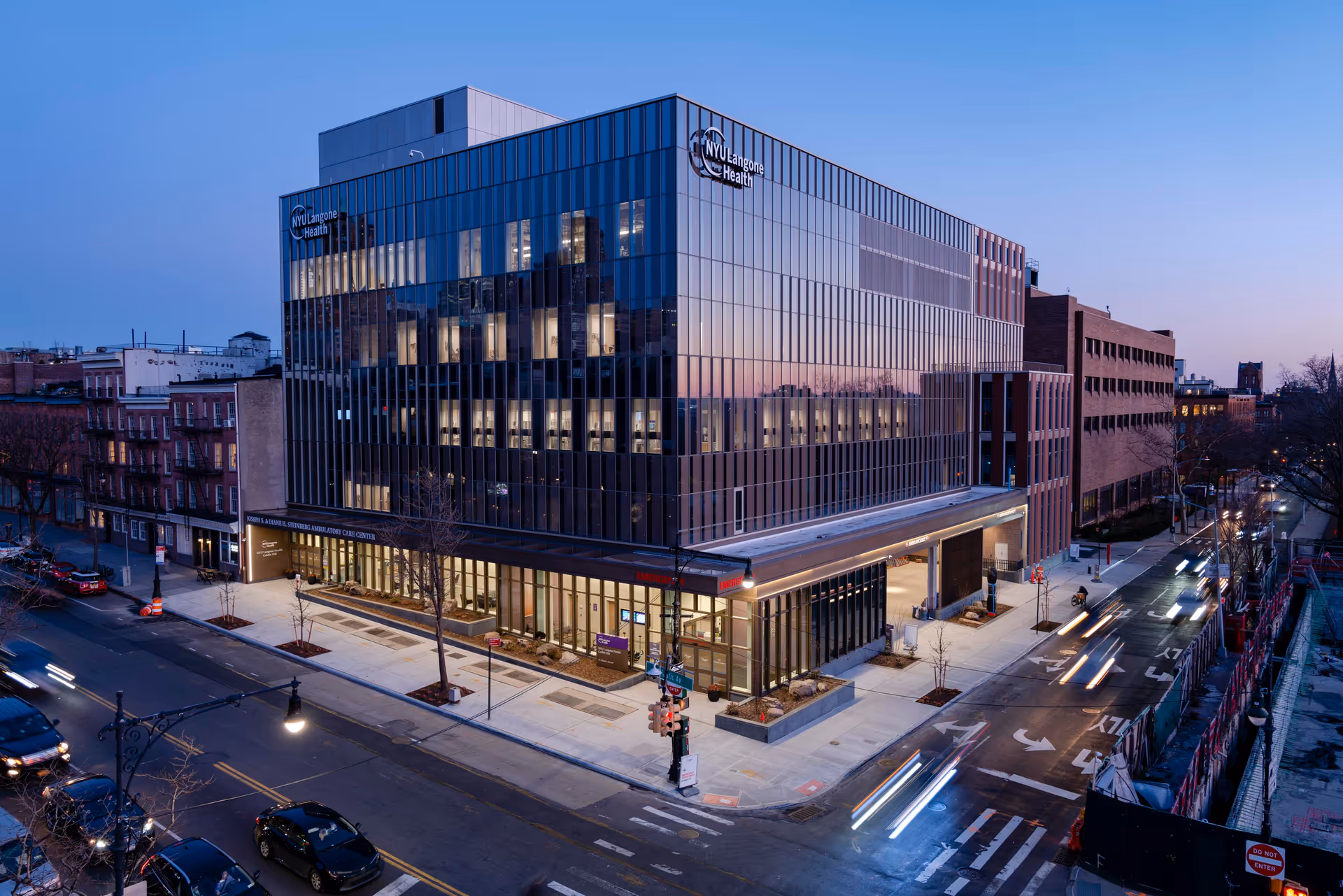 Front view of the Perlmutter Cancer Center in a glass building at dusk.