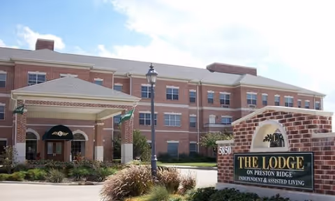 Brick senior living facility exterior with covered entrance and front sign.