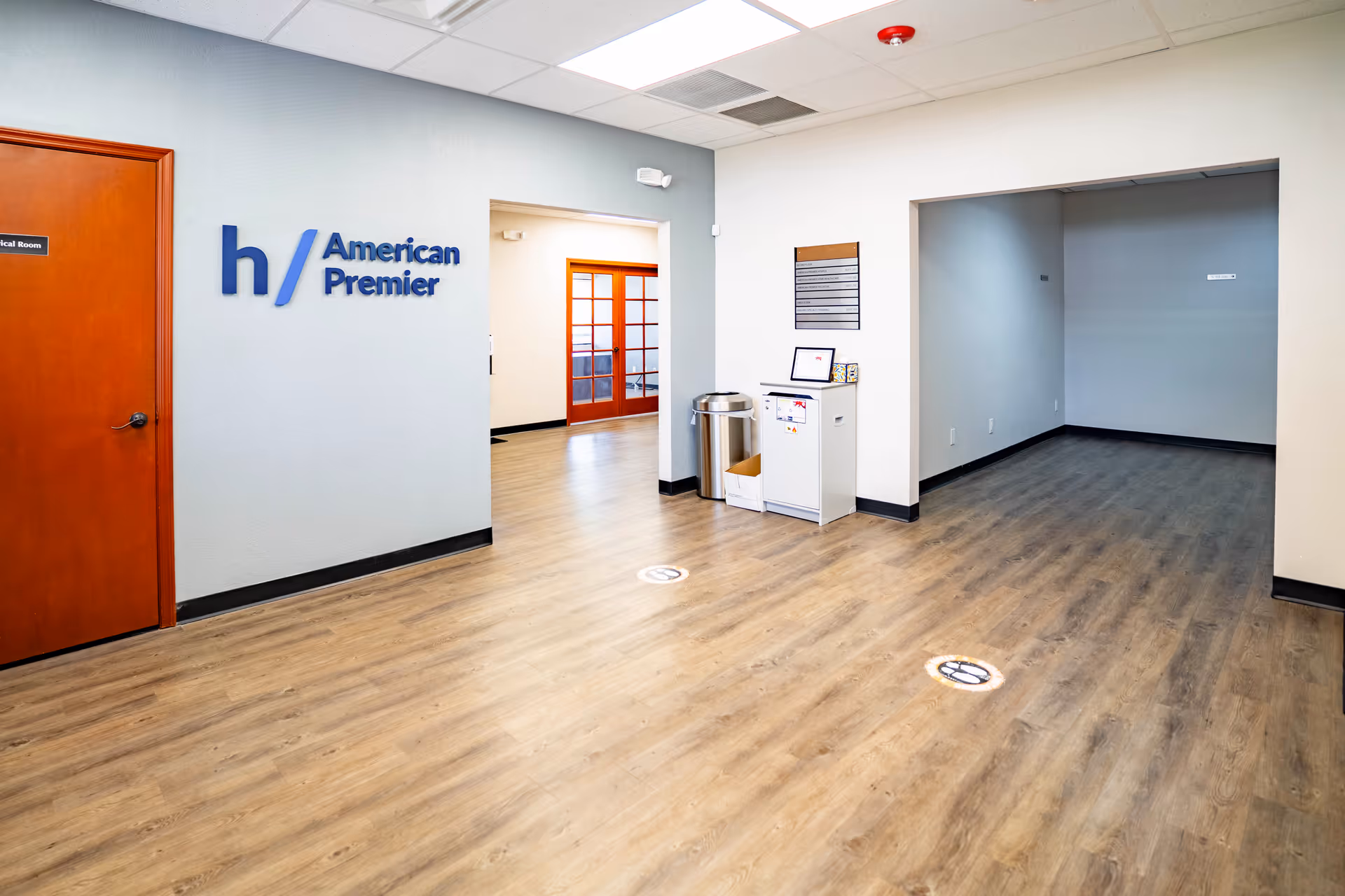 Interior hallway at American Premier facility featuring the blue logo, doors, and a small service area.