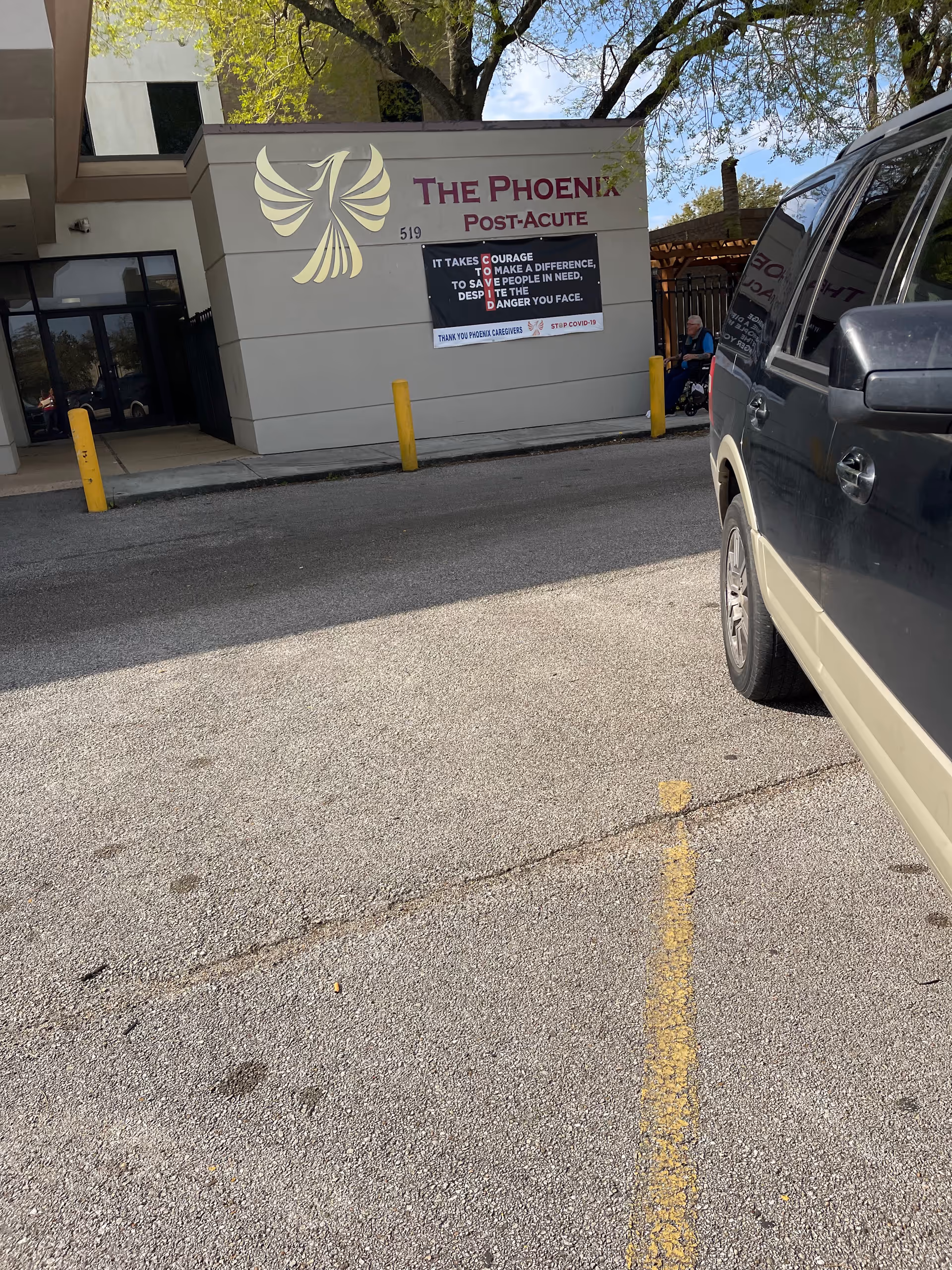 Exterior view of The Phoenix Post Acute Care building with signage and a parked vehicle.