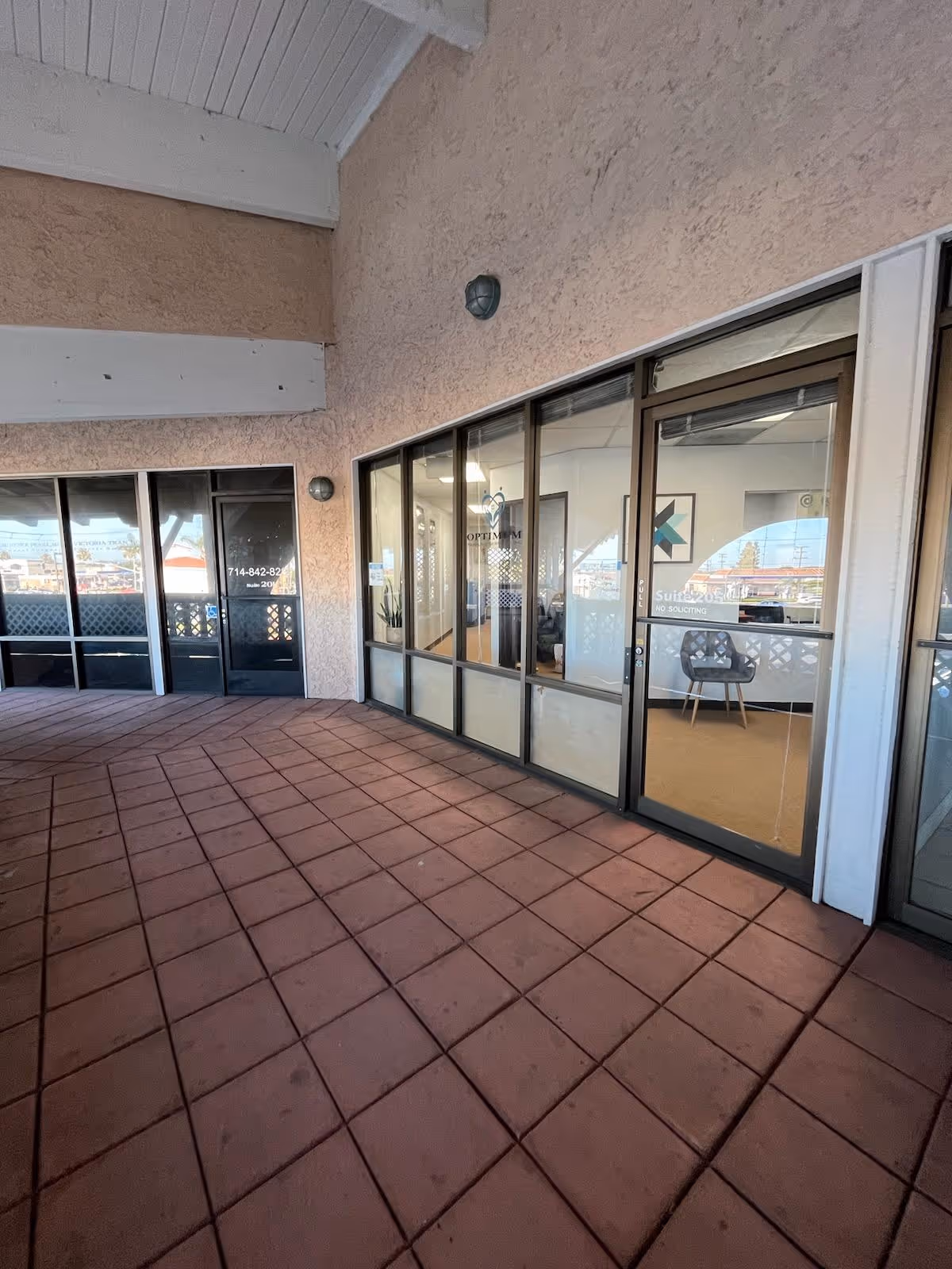 Covered outdoor corridor with glass doors leading into a senior care facility.