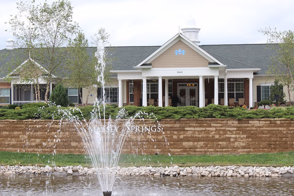 Front exterior of a senior living building with a fountain and landscaped entrance.