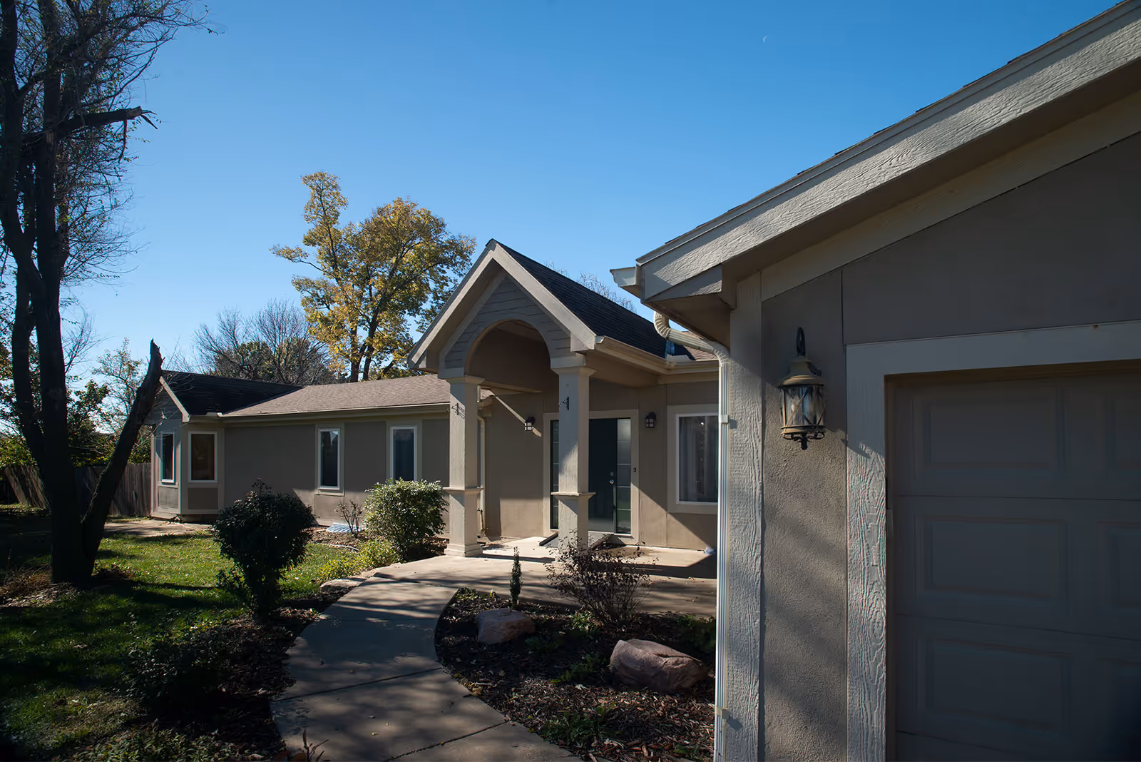 Single-story senior living facility exterior with curved walkway and front entrance under a portico.
