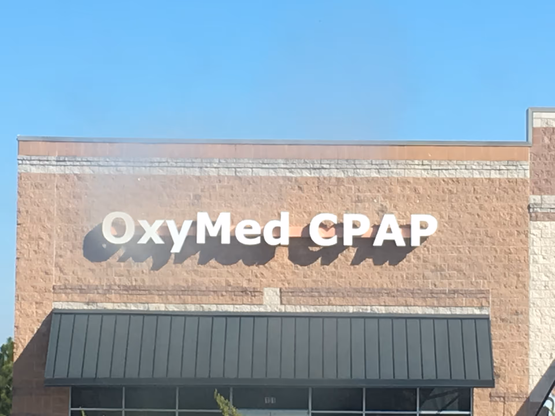 Exterior view of a brick building with OxyMed CPAP sign and awning