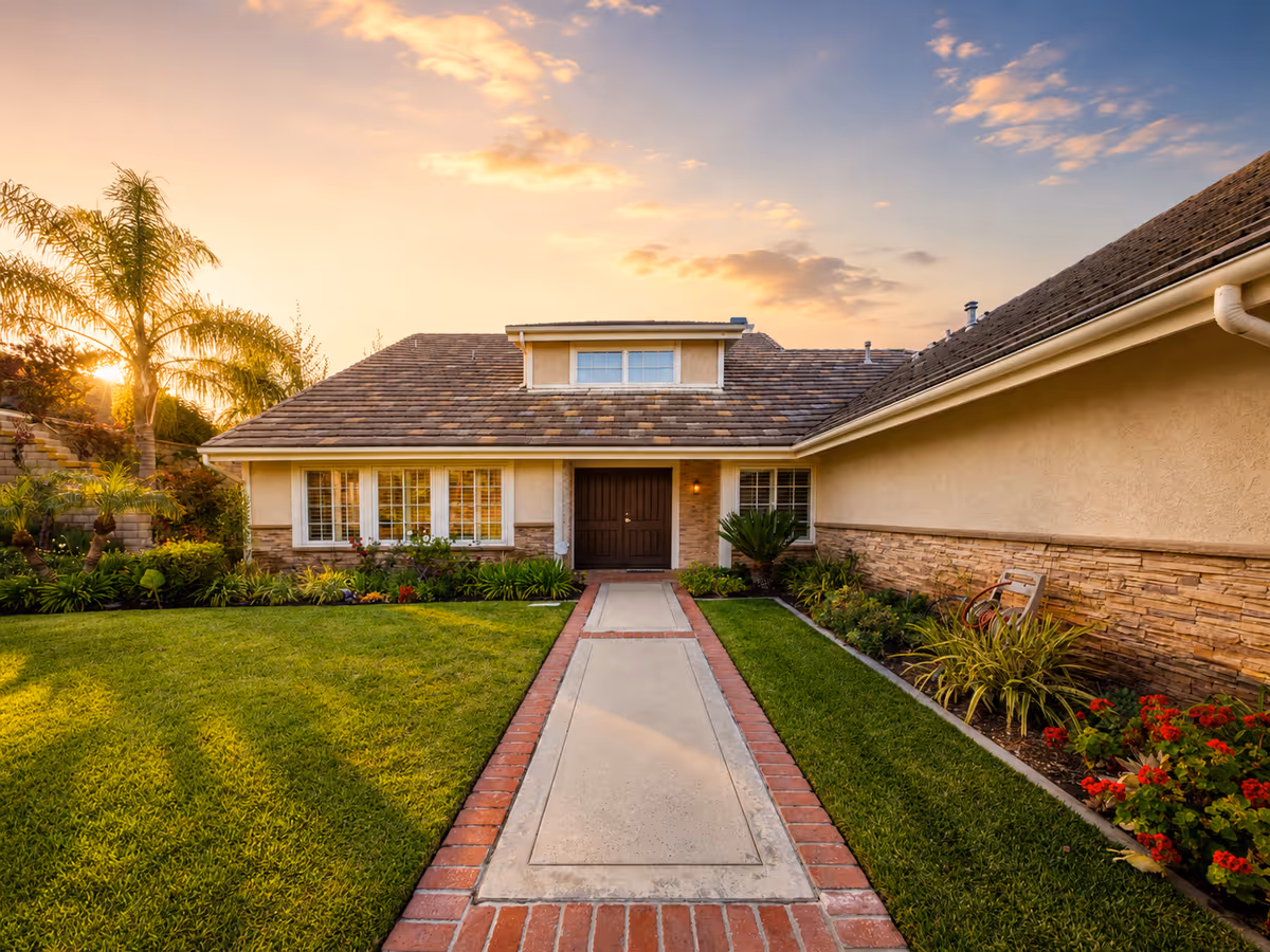 Front view of a single-story building with a central door and landscaped walkway at sunset.