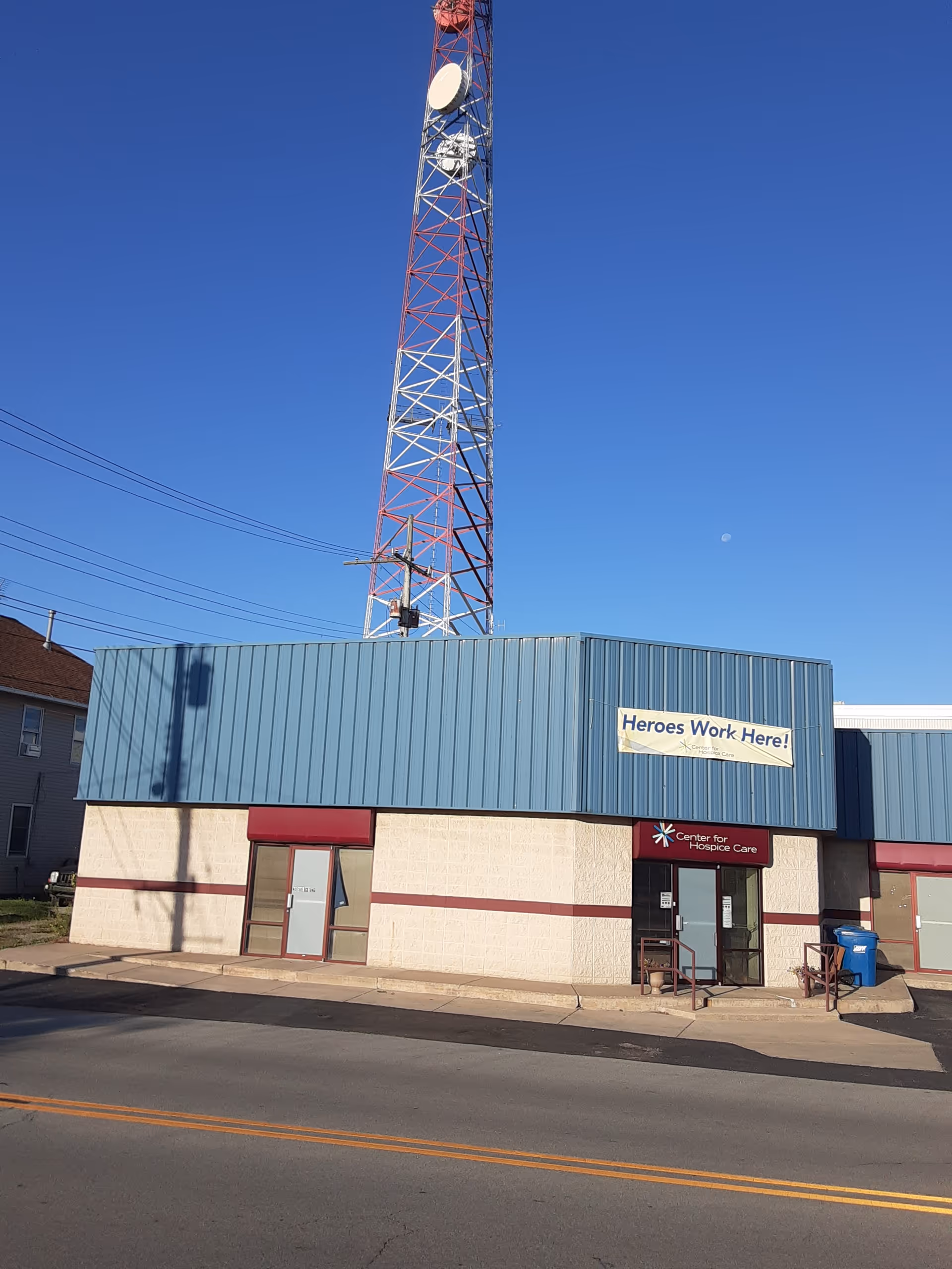 Exterior view of Center for Hospice Care building with blue siding, sign, and a radio tower.