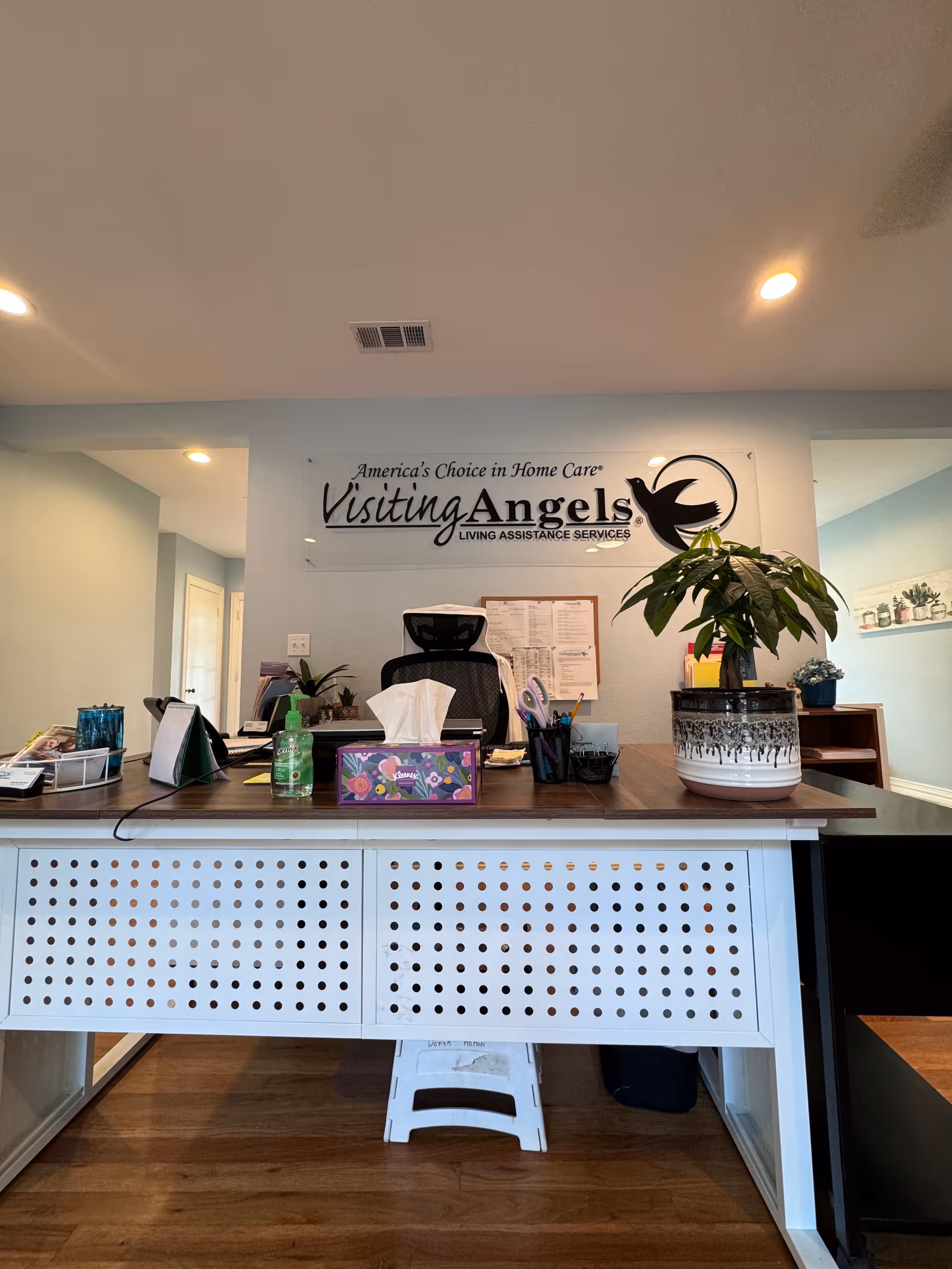 Reception area of Visiting Angels Senior Home Care Granbury featuring desk, sign, and plant.