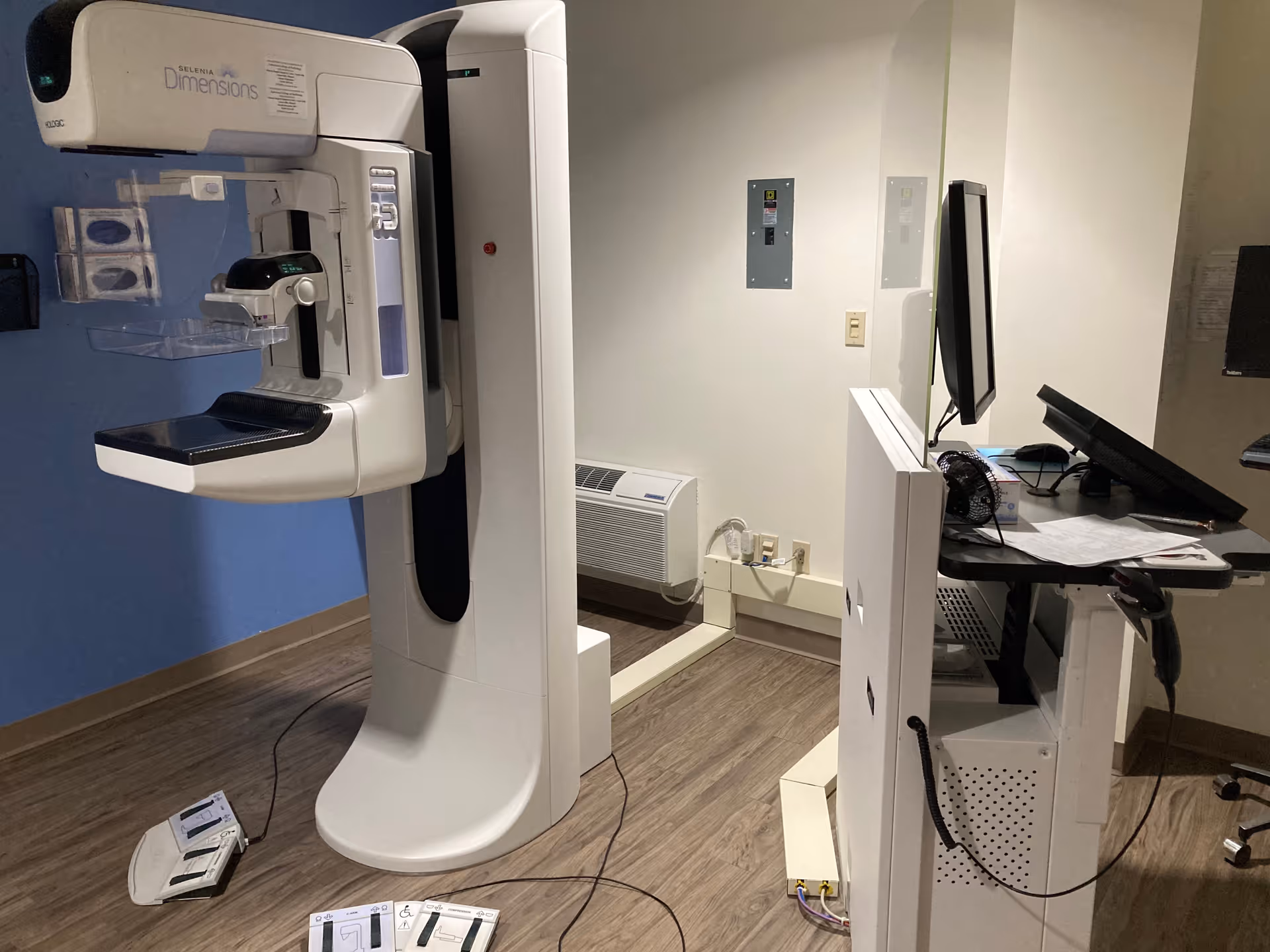 Medical imaging room with a mammography machine and a computer workstation.