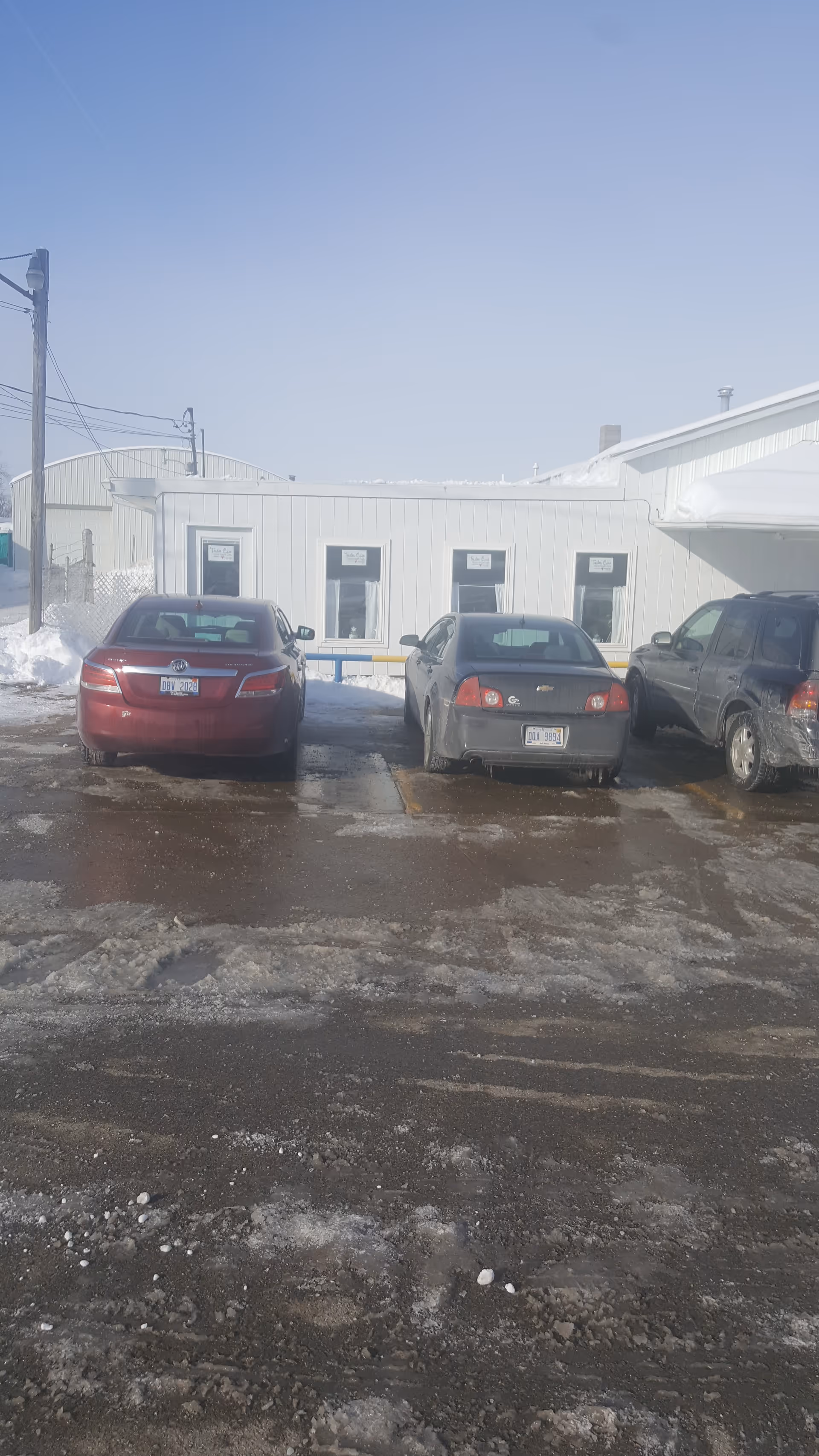 Exterior view of a building with parked cars in a snowy lot.