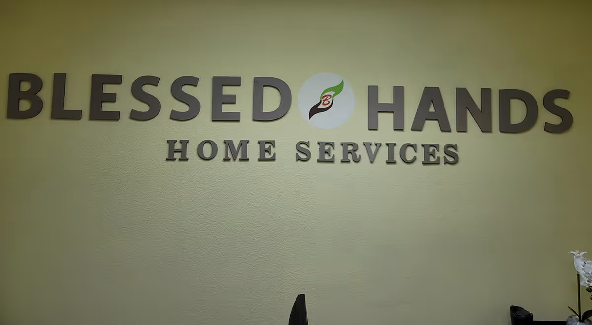 Sign reading Blessed Hands Home Services on a pale green wall.